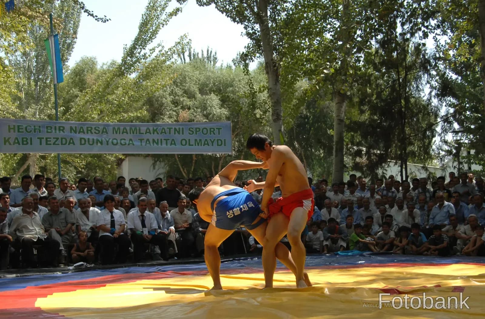Athletes wrestling on a mat outdoors