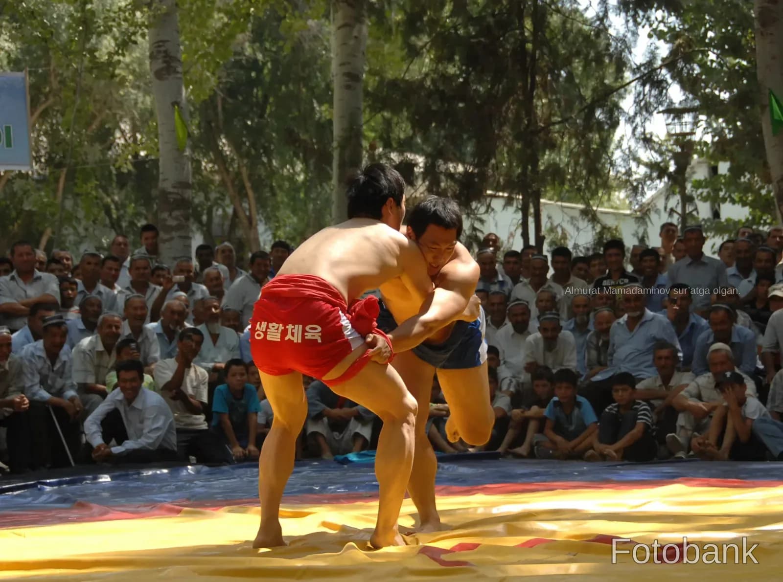 Athletes wrestling on a mat outdoors