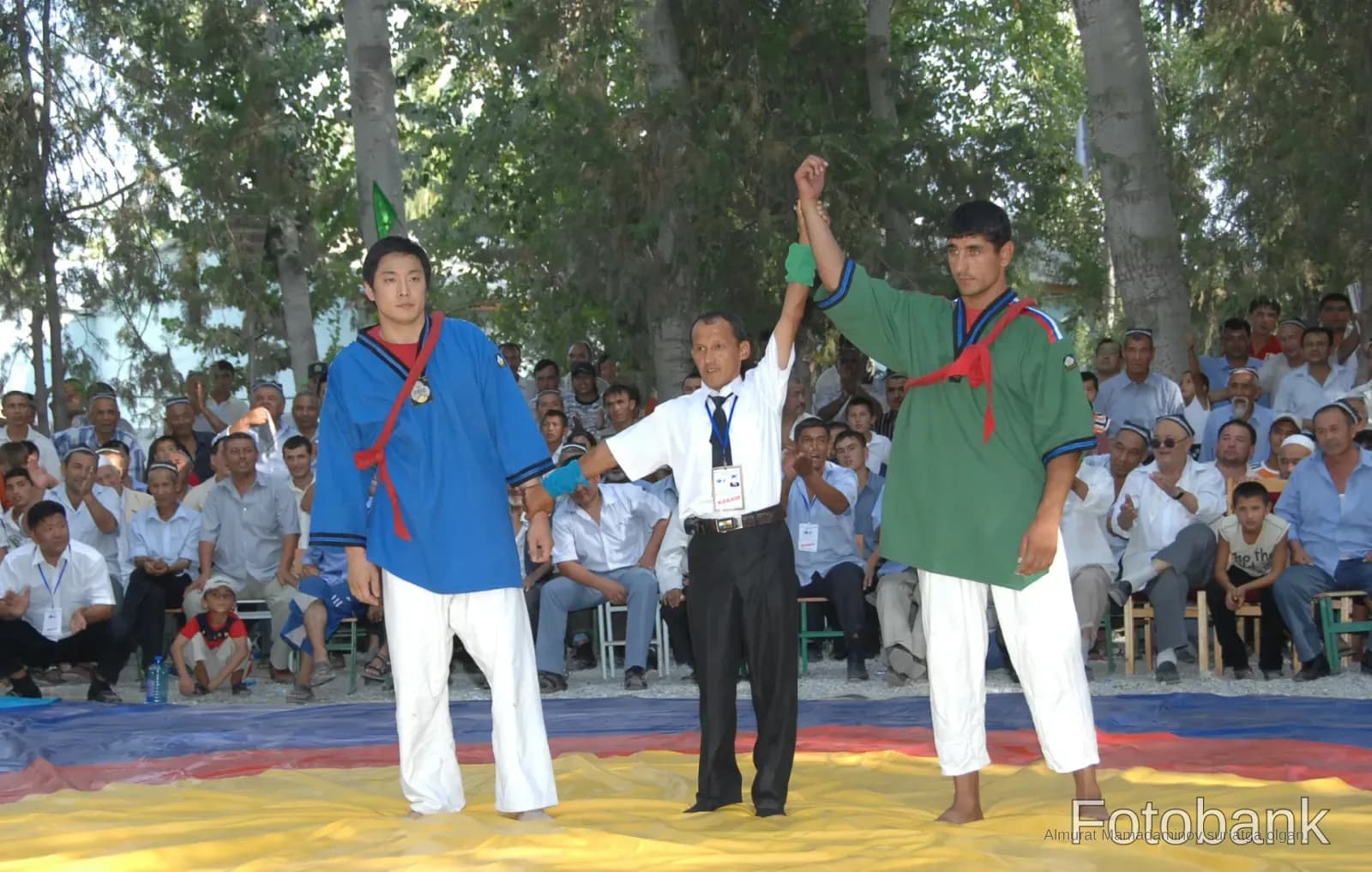Referee and athletes on a mat outdoors
