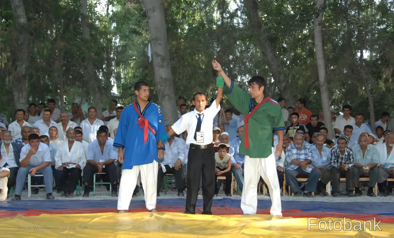Referee holding up the hand of a wrestling winner during a competition