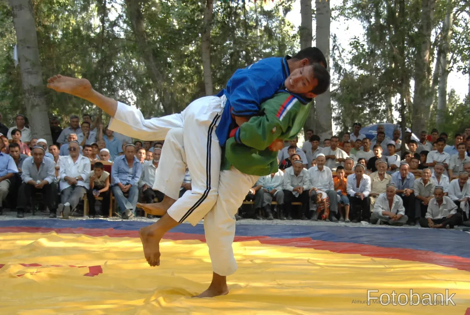 Two competitors grappling on a mat outdoors