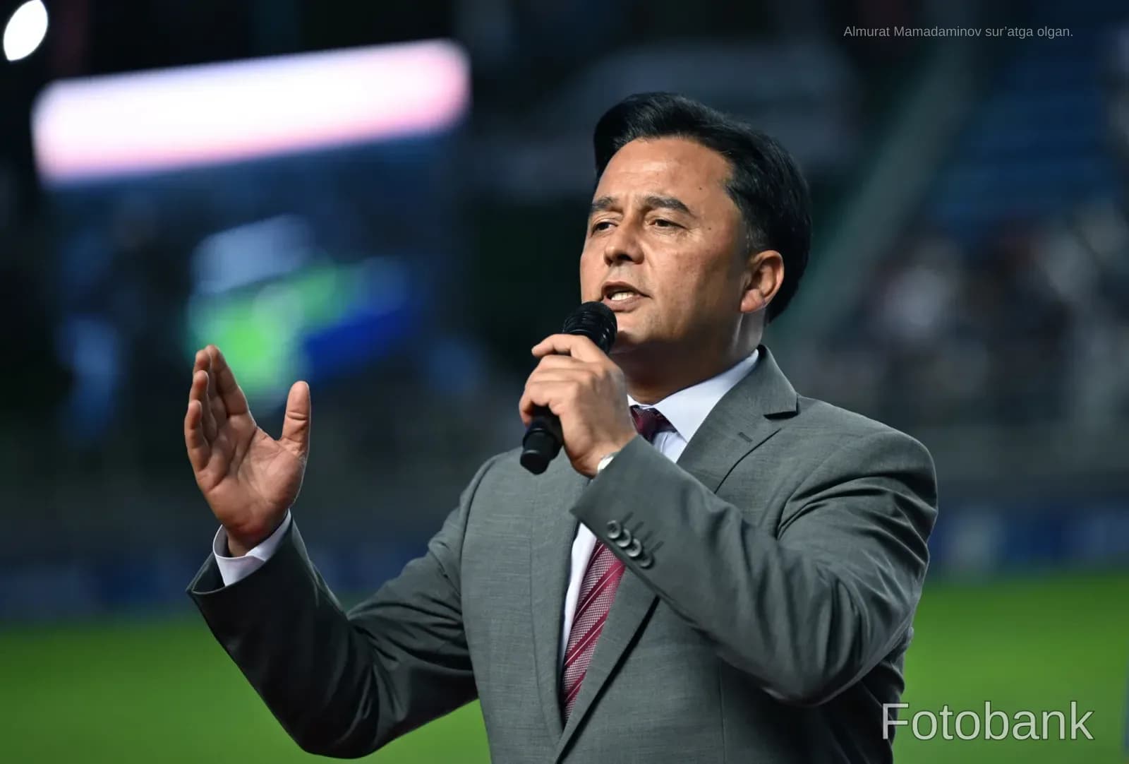 Man speaking into a microphone at a stadium