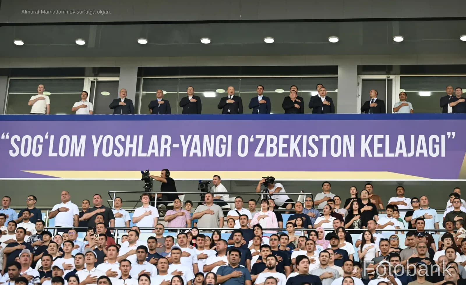 People gathered in a stadium with hands on chests