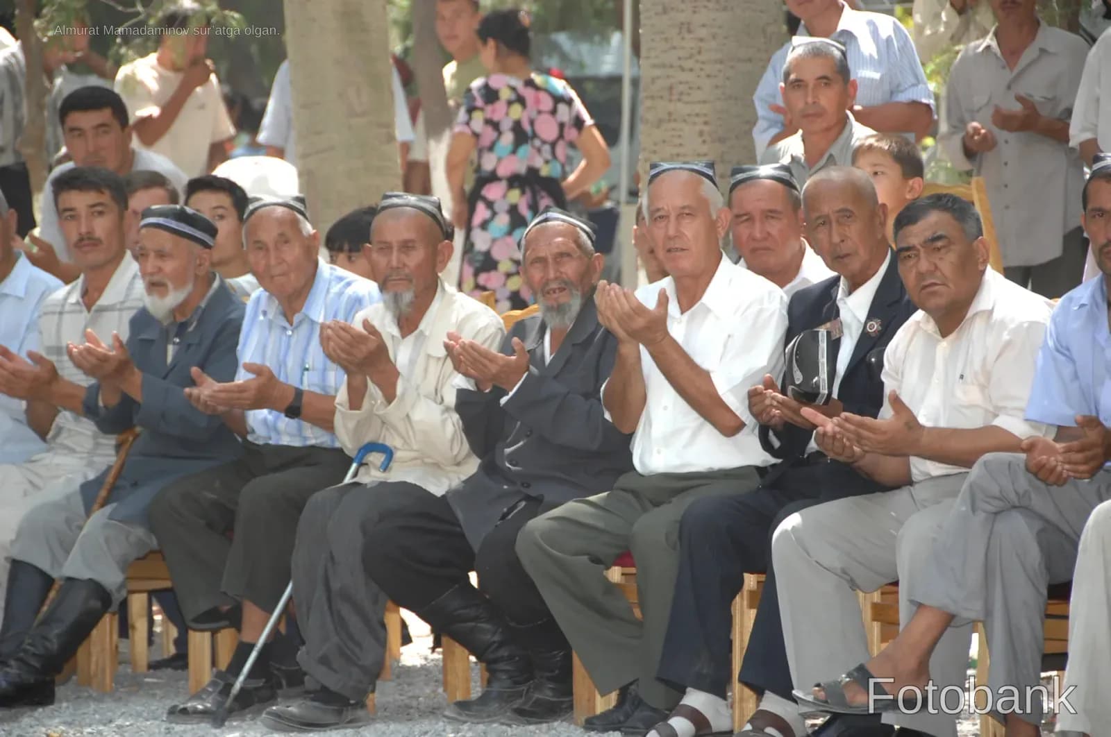 Group of men sitting outdoors with hands raised