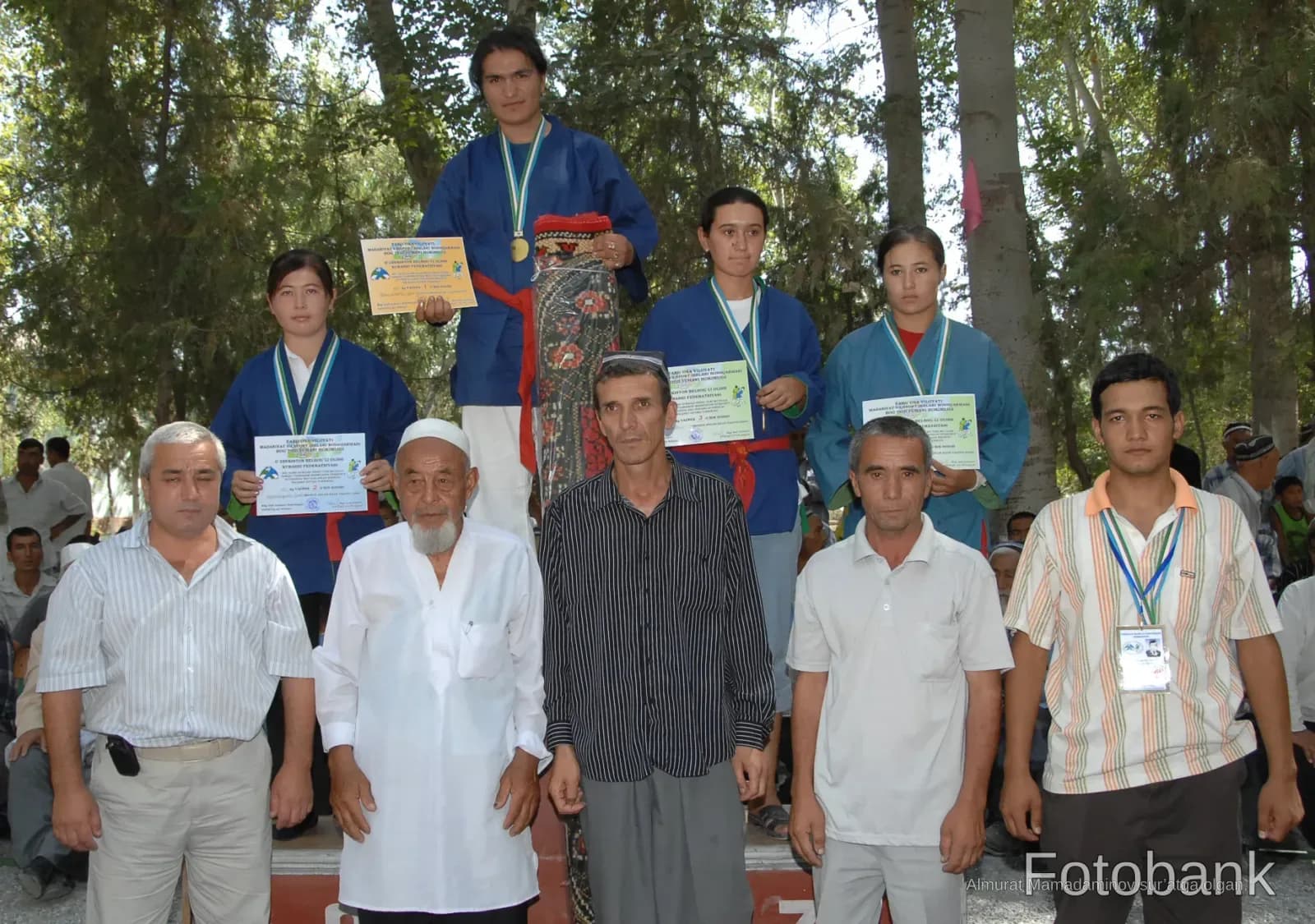 Group of people posing outdoors holding awards and medals
