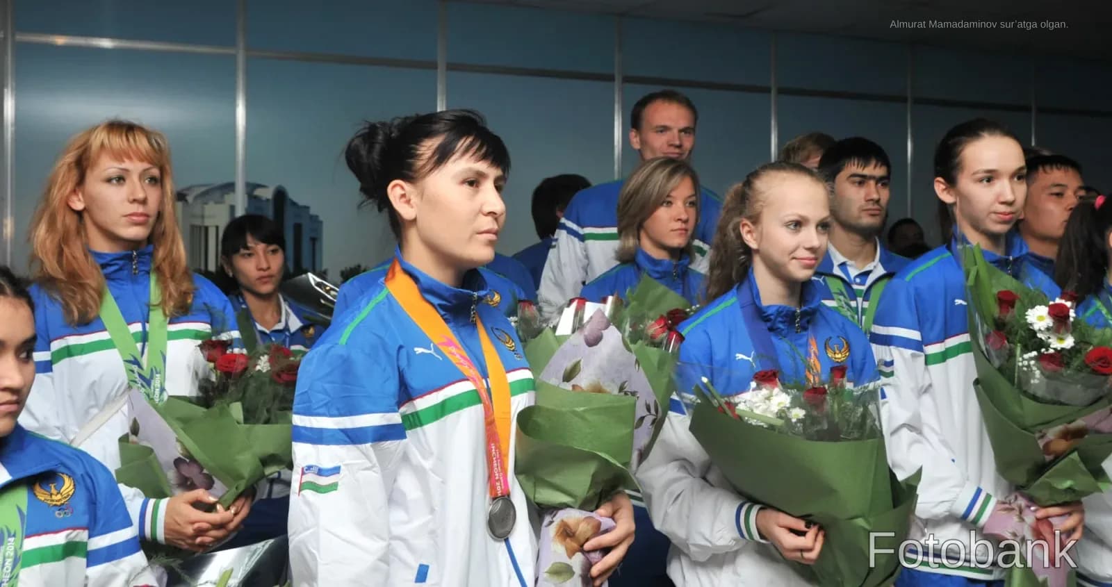 Группа спортсменов, стоящих вместе и держащих букеты цветов