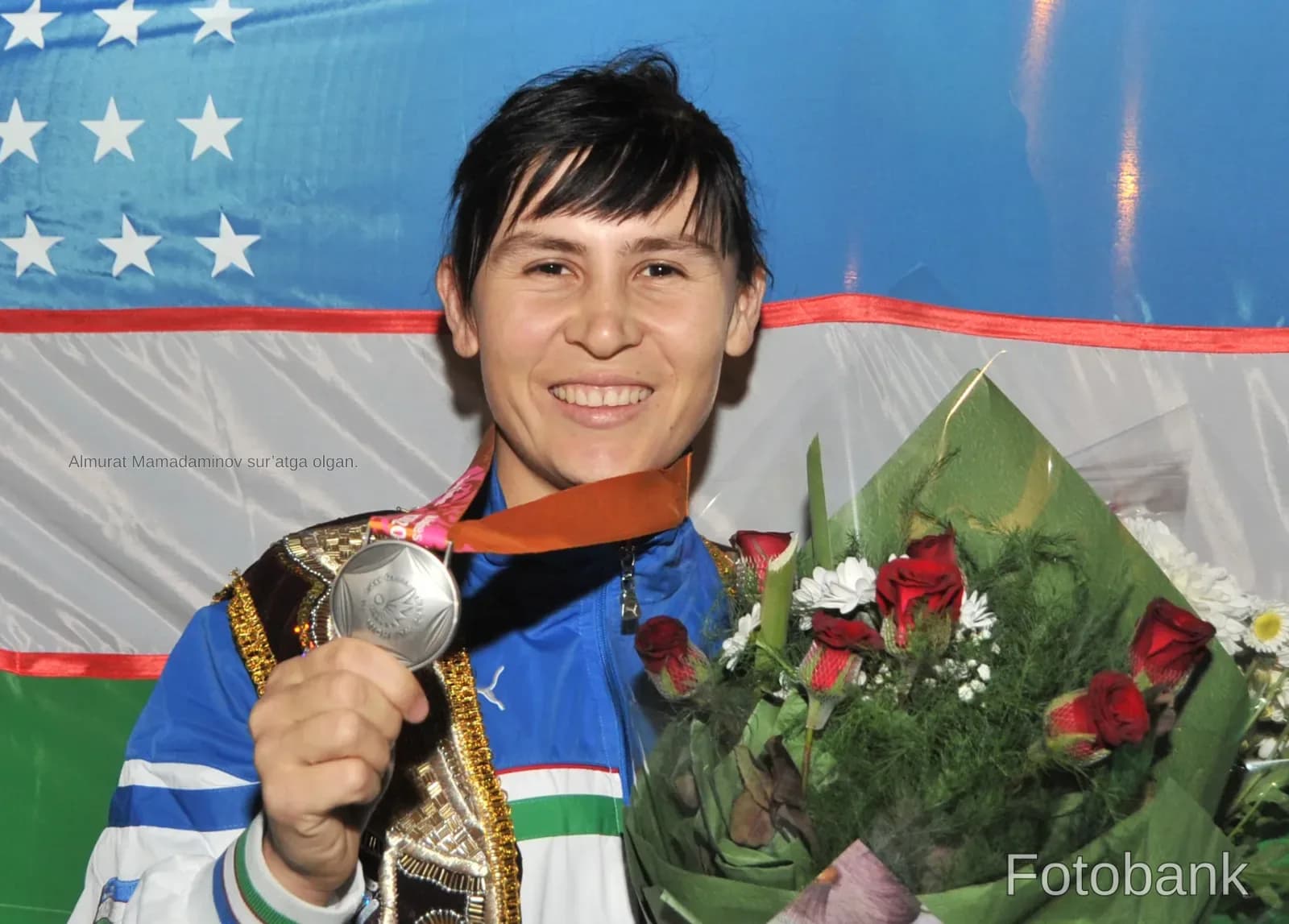 Спортсмен, держащий медаль и букет цветов перед флагом