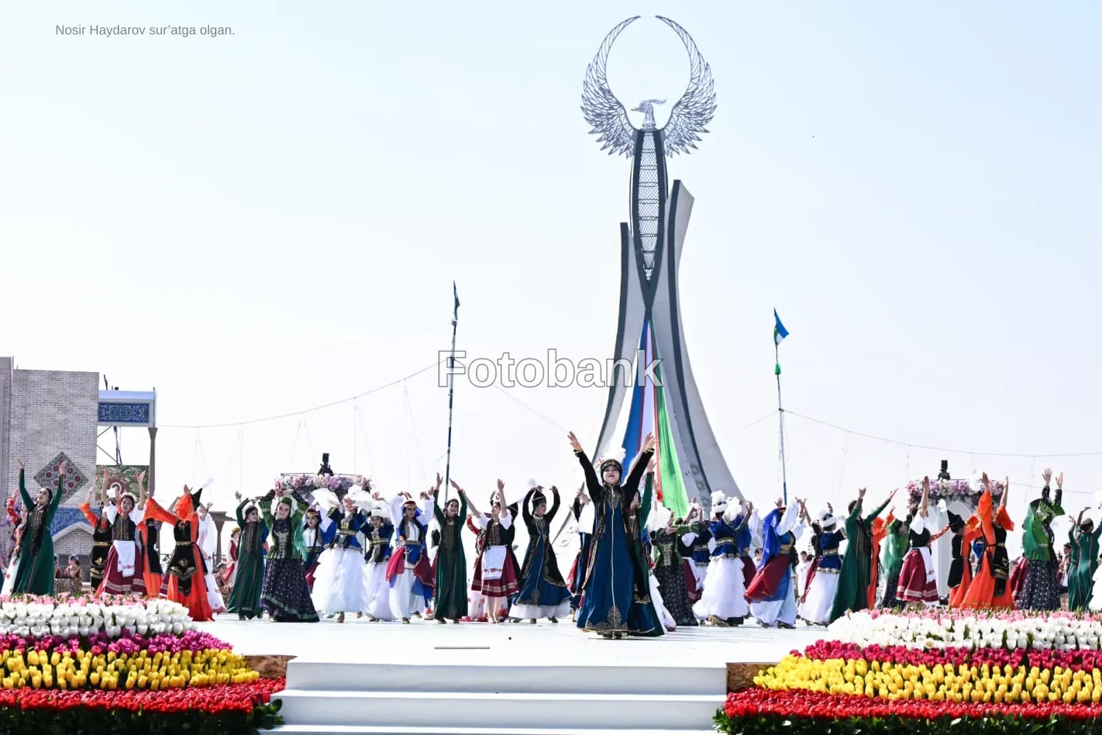 People performing traditional dances outdoors near a large monument