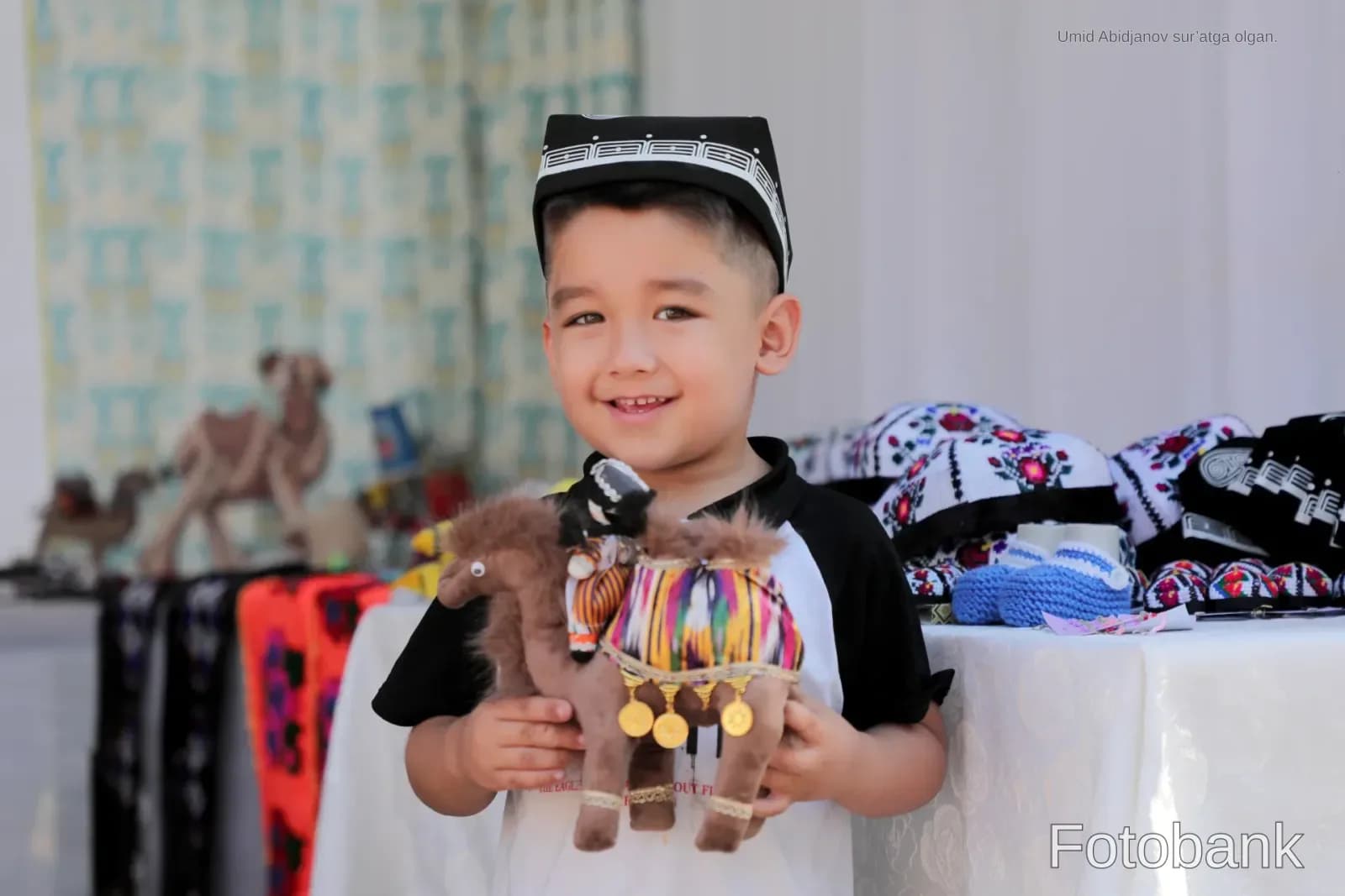 Улыбающийся мальчик держит игрушечного верблюда