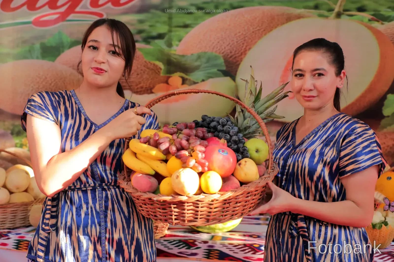 Две женщины с большой плетеной корзиной, наполненной свежими фруктами