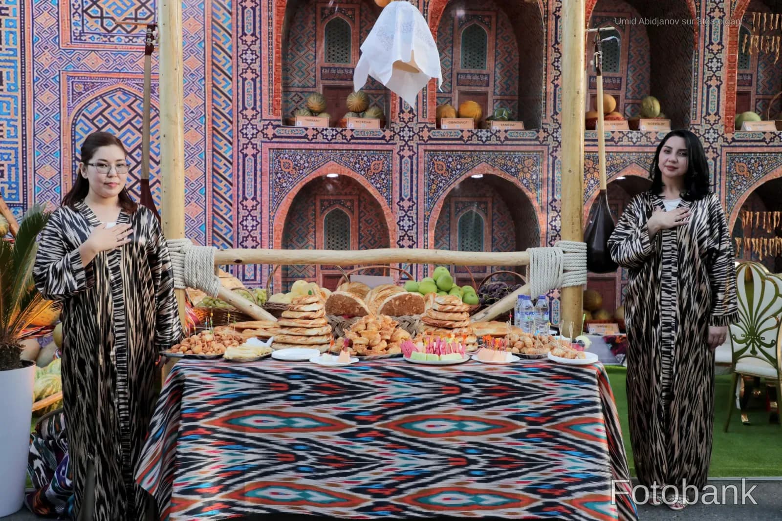 Women standing beside a table laden with food and pastries