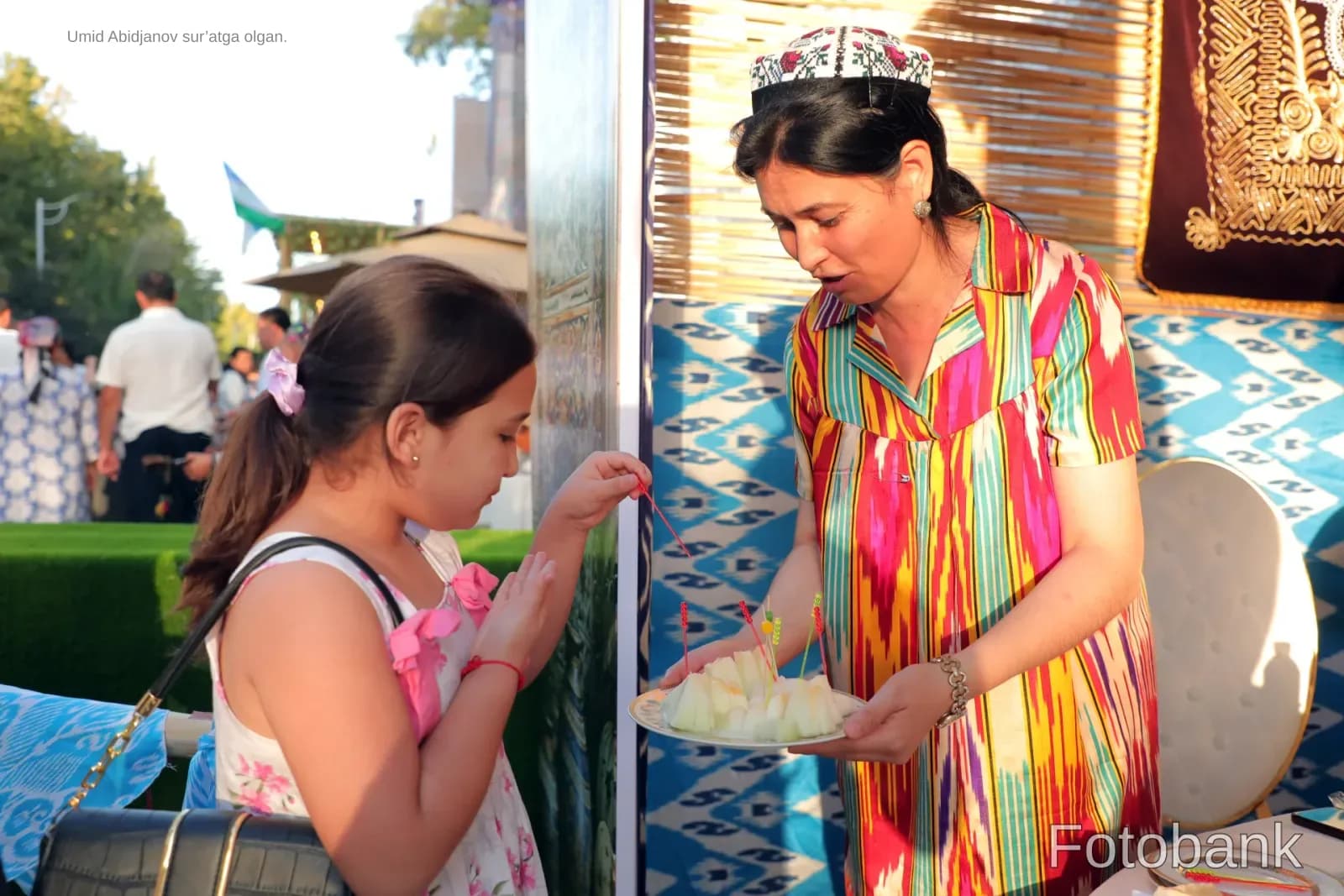Woman in traditional attire offering food to a child