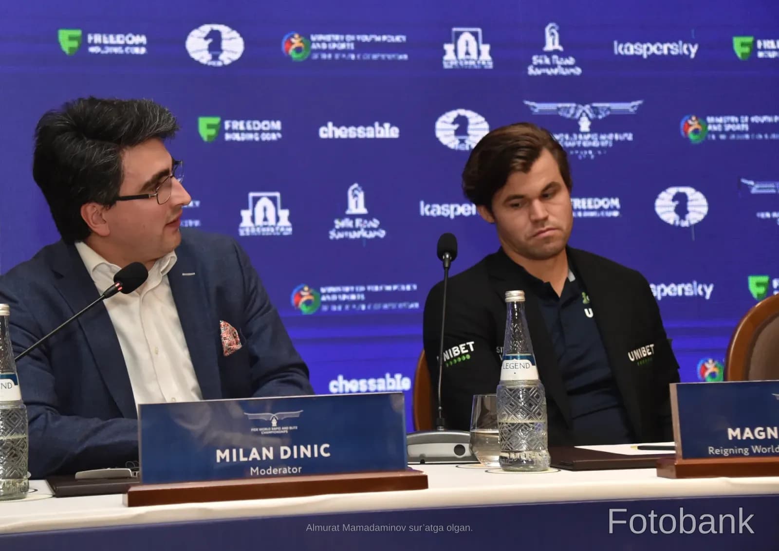 People participating in a conference with microphones and nameplates