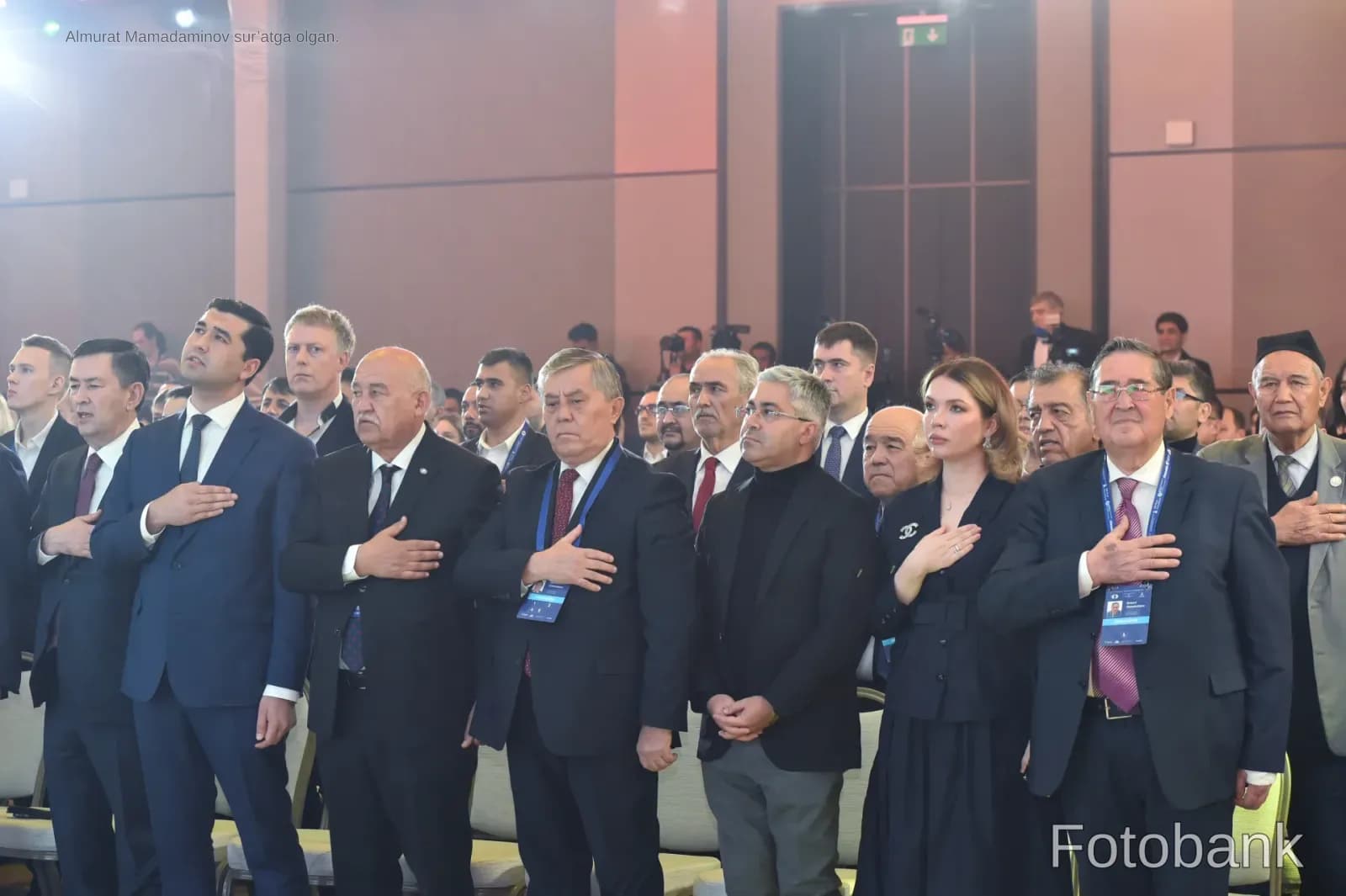 Group of people standing and placing hands on chests during indoor gathering