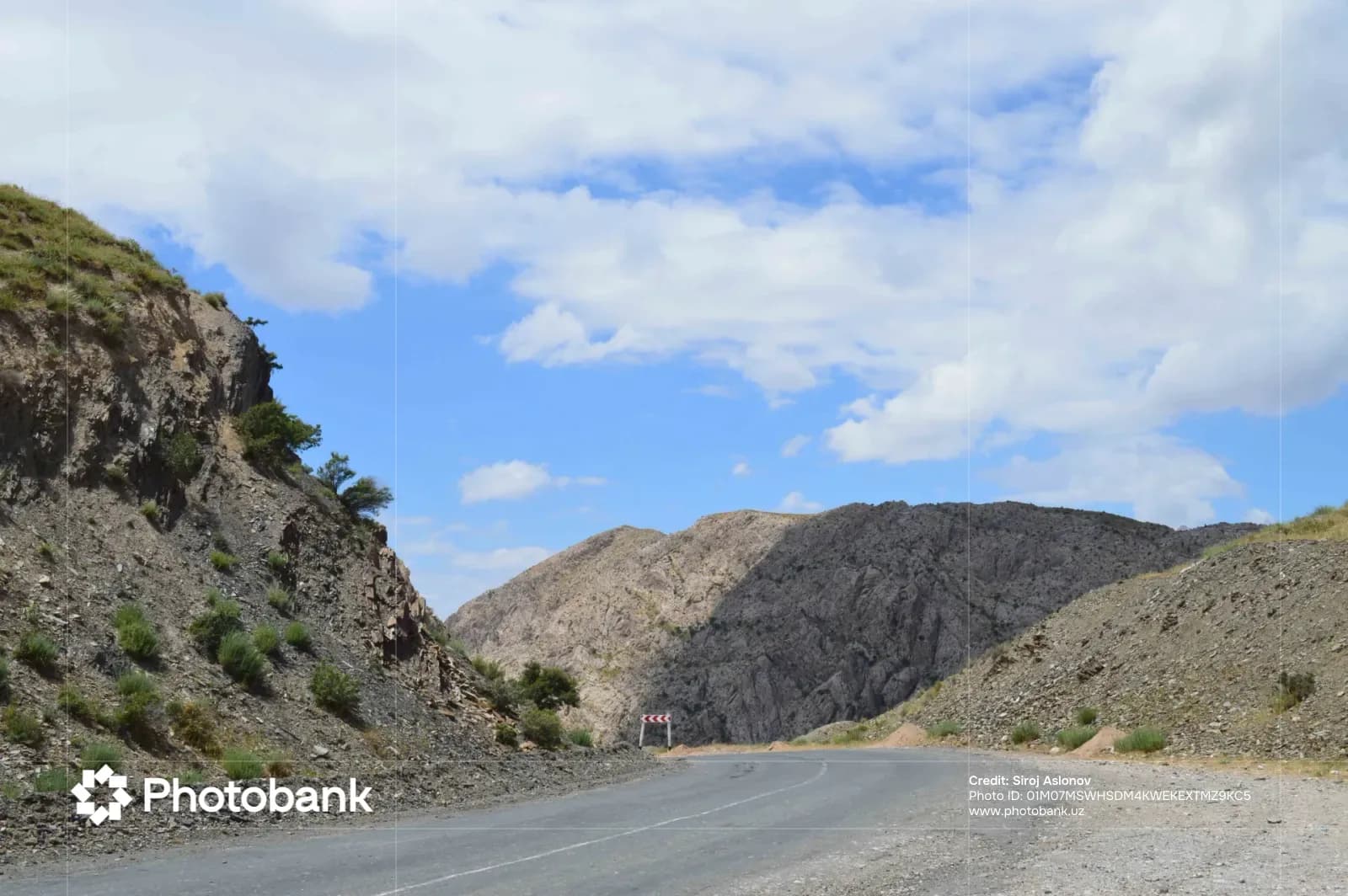 Paved mountain road curving through rocky hills and sparse vegetation