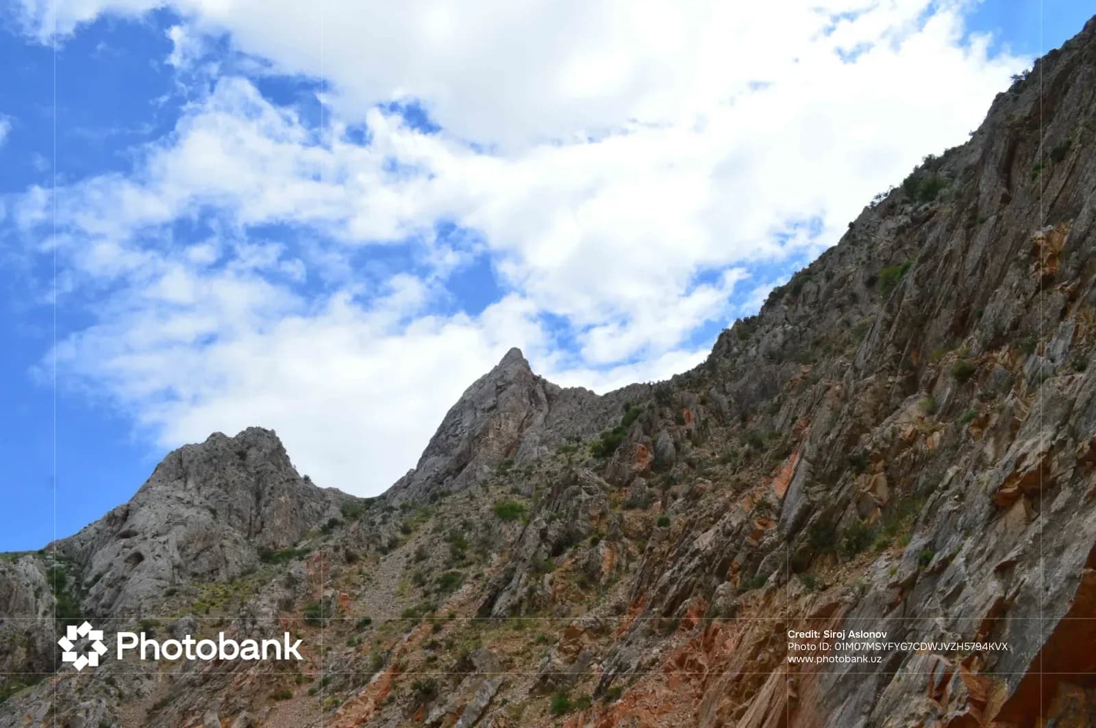 Rugged mountain slope against a cloudy blue sky