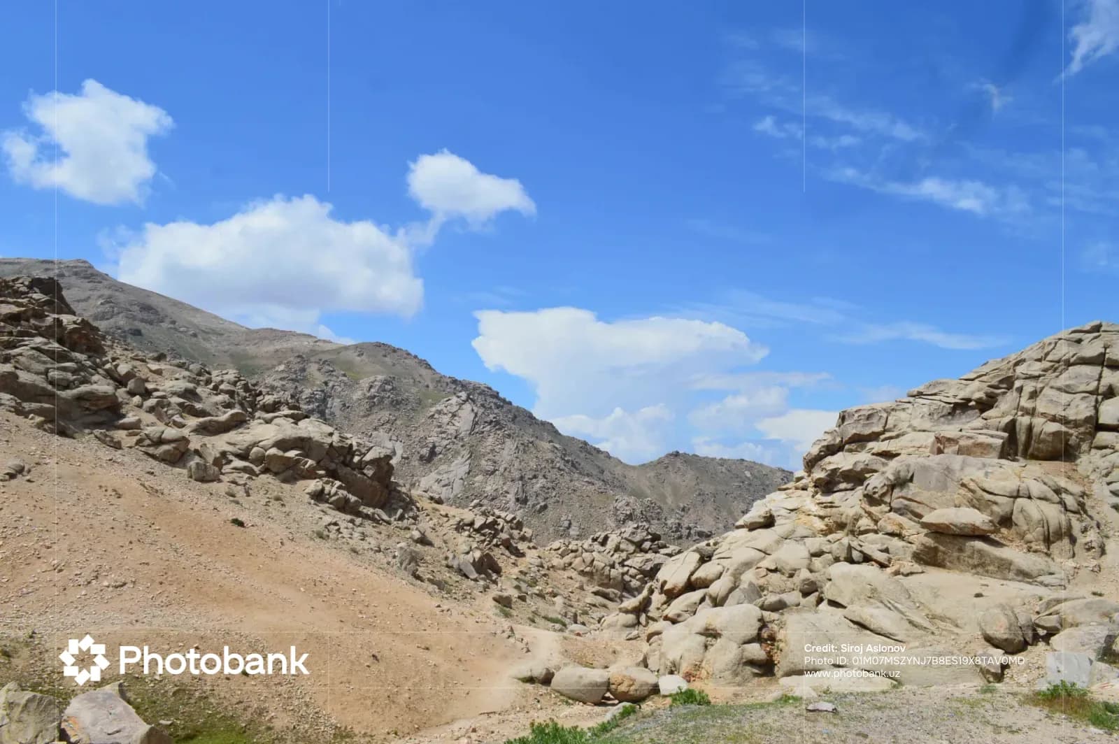 Rocky mountain landscape under a blue sky with white clouds
