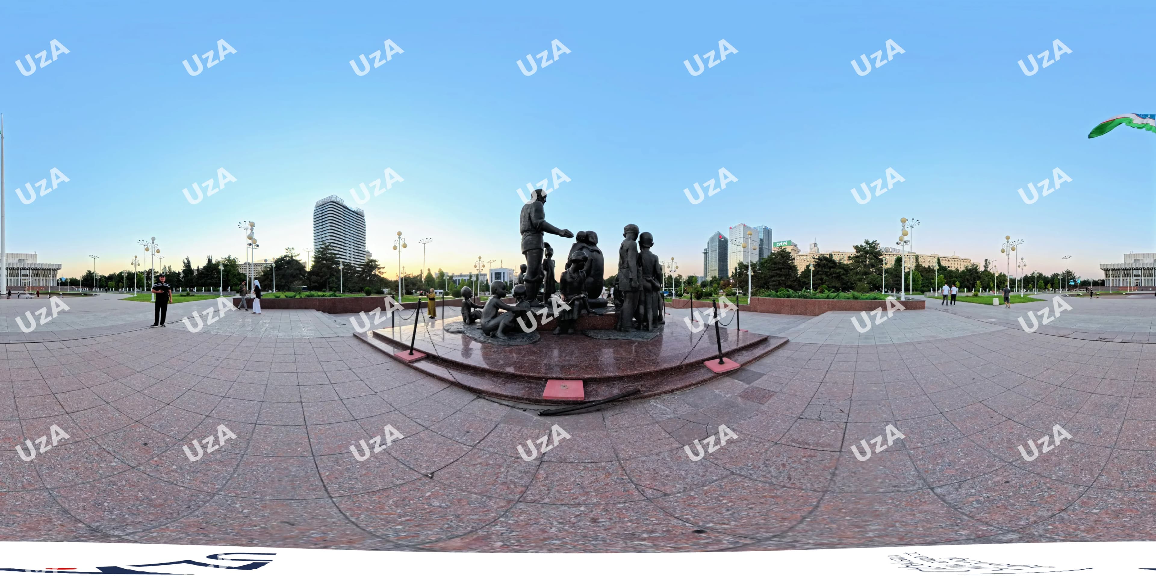 Public square with a bronze monument surrounded by modern buildings