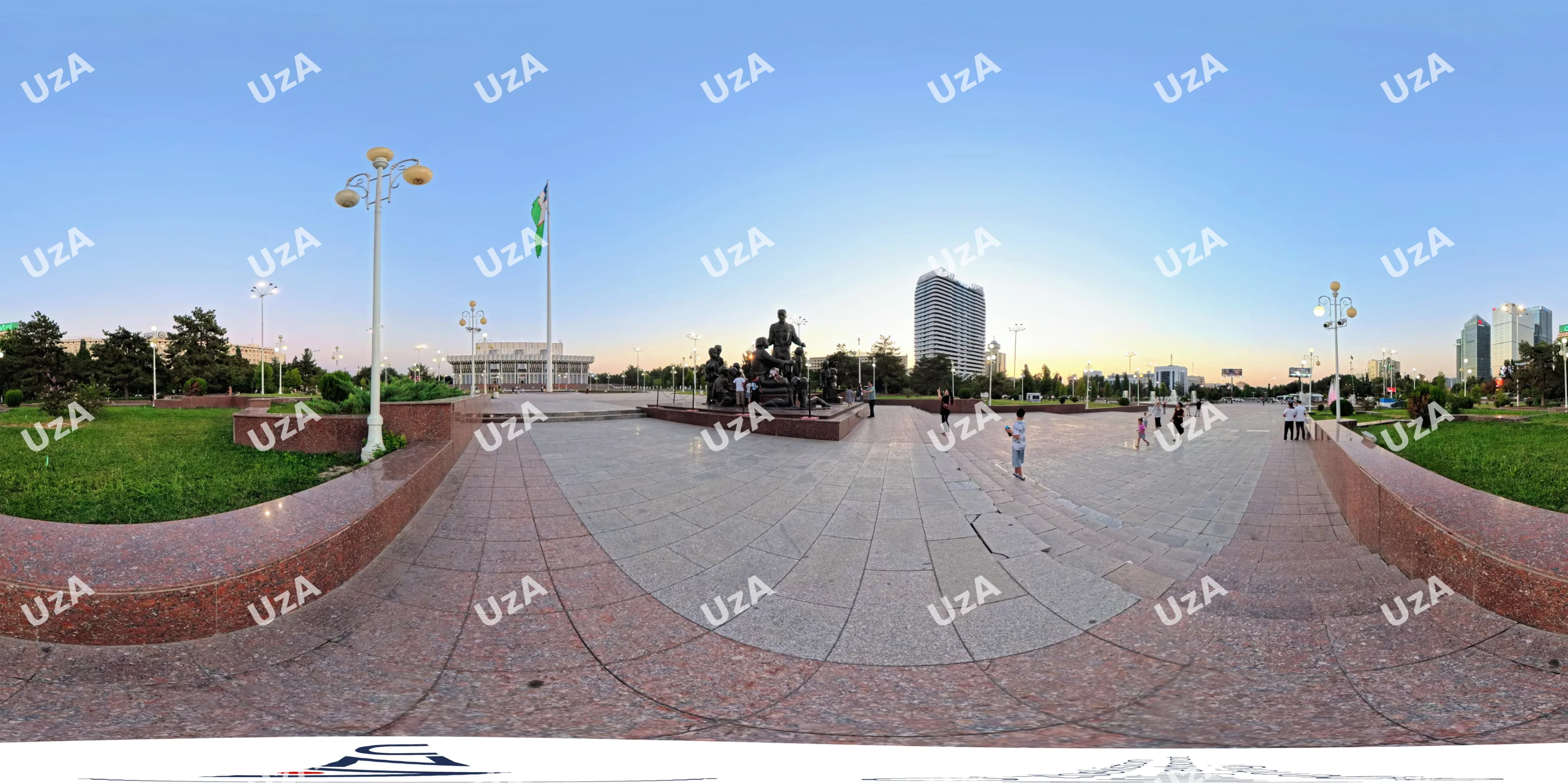 People walk on a public plaza with a monument and flag