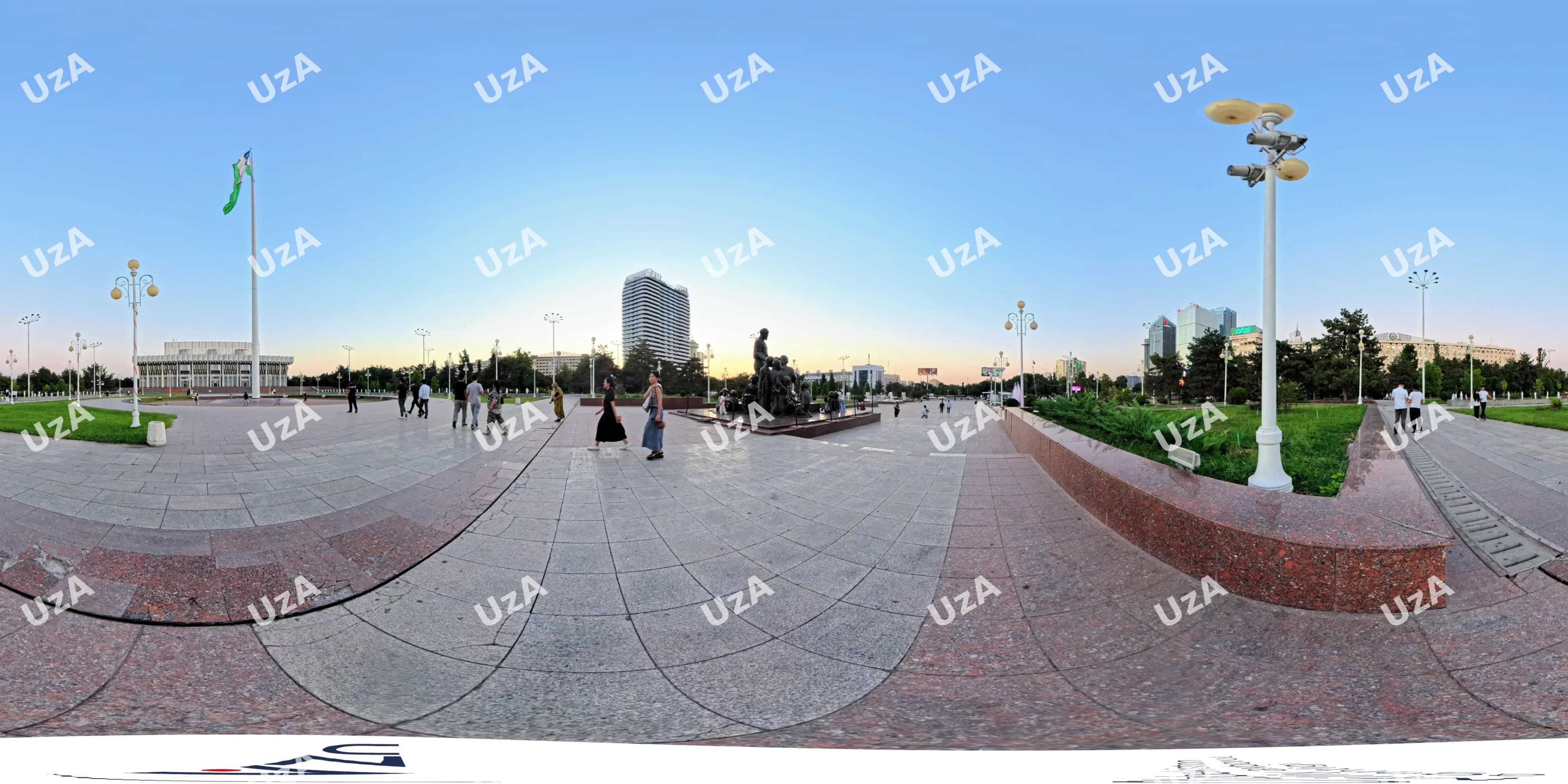 People walking on a paved city square with a monument and flag