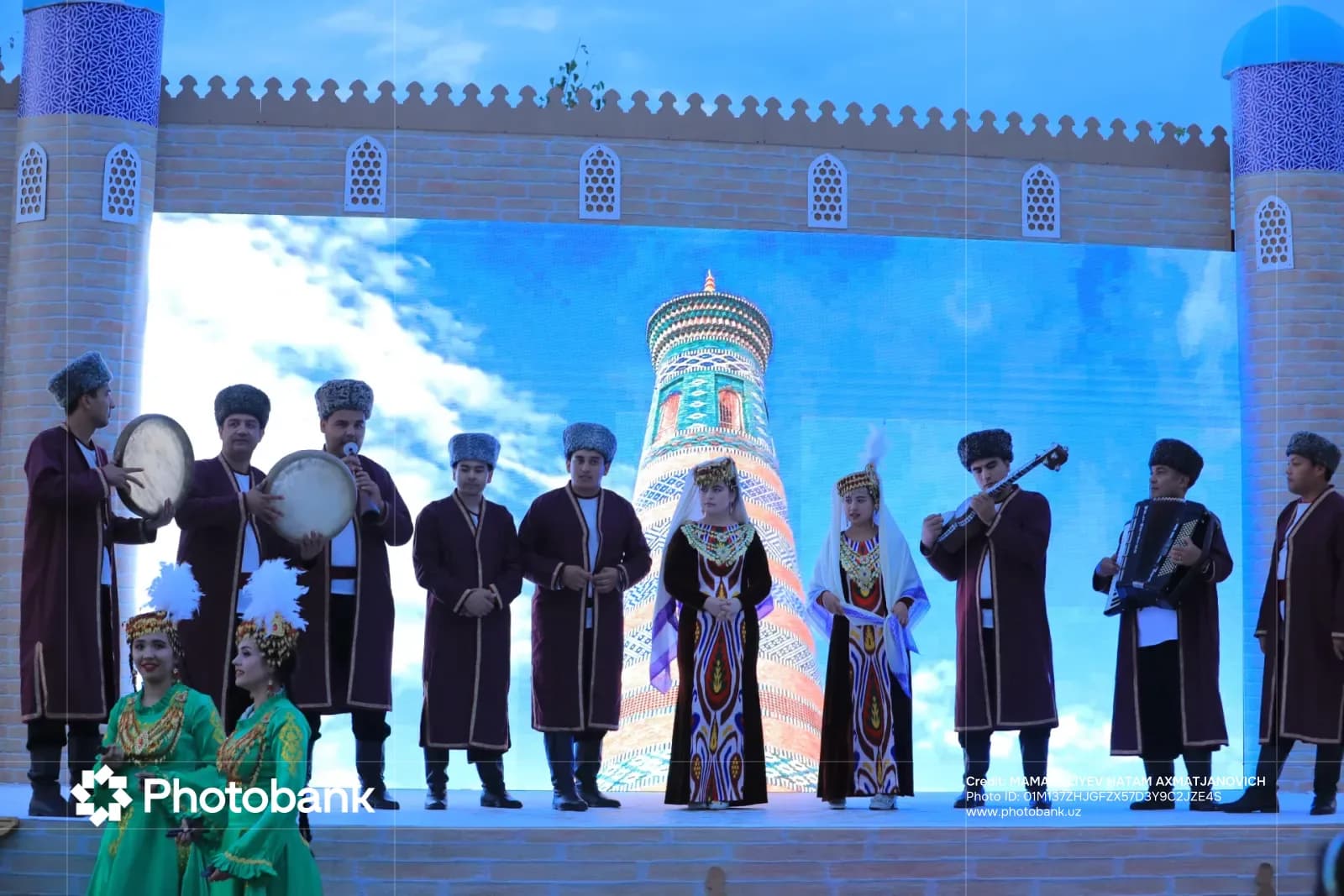 Performers in traditional clothing on stage with large backdrop
