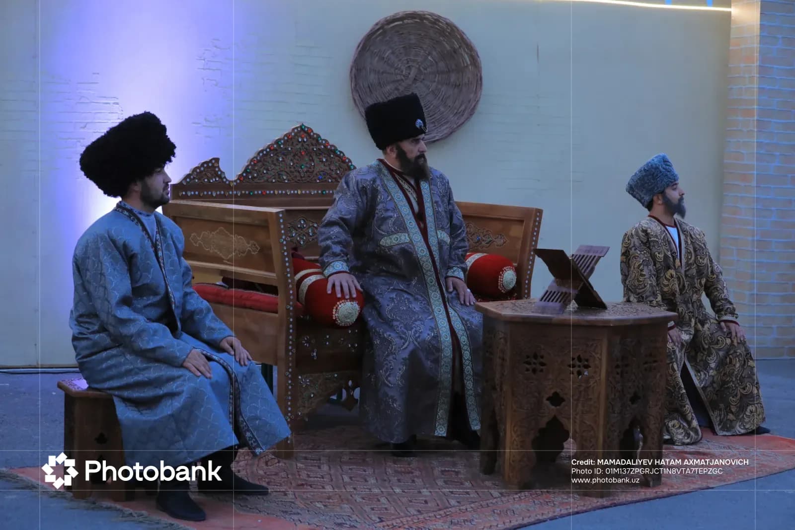 Men in traditional clothing sitting on wooden furniture indoors