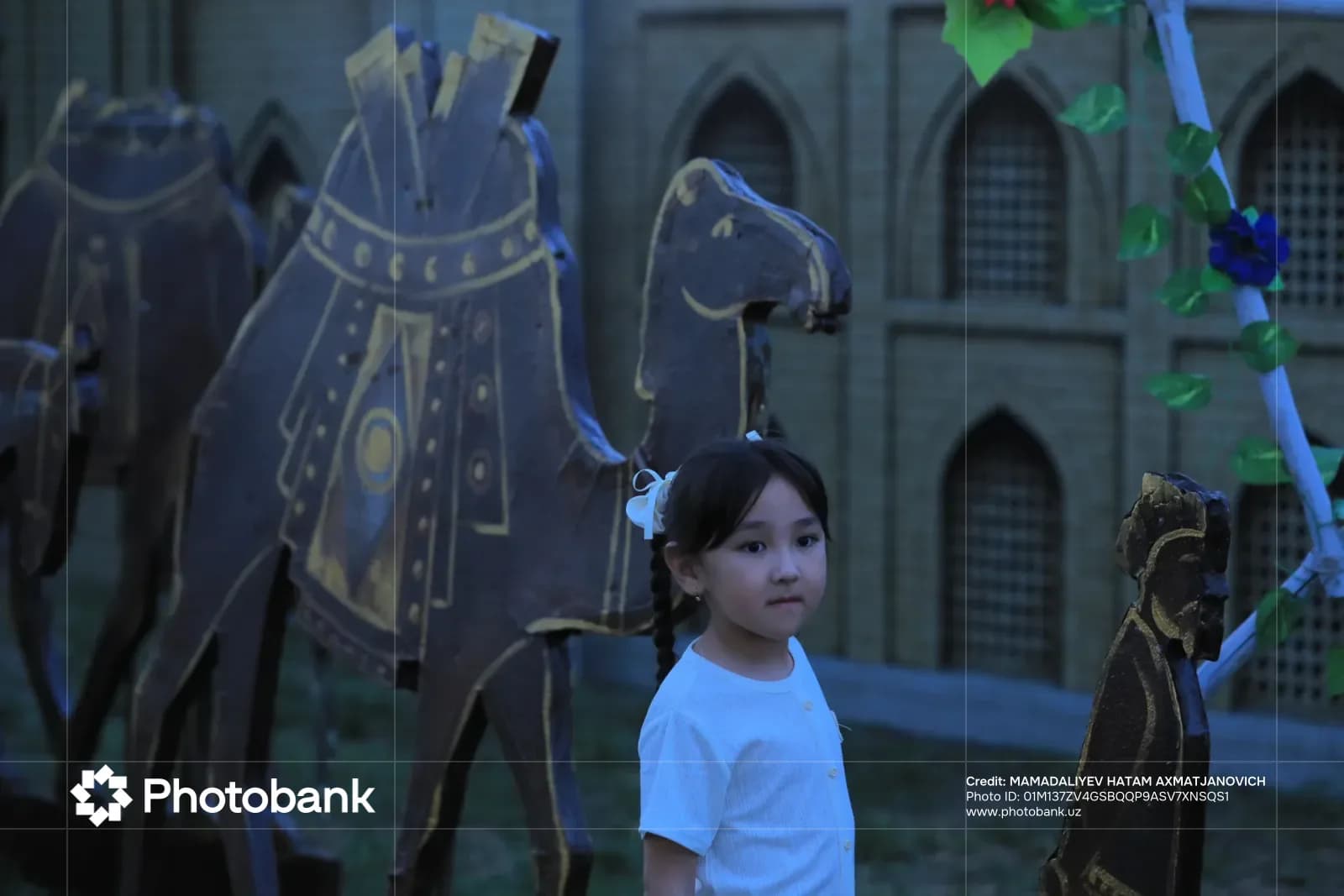 Young girl standing near decorative camel sculptures and architectural models