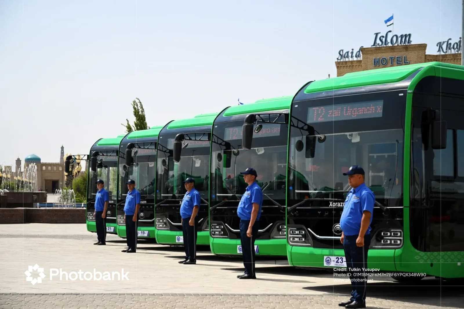 Uniformed staff standing in front of green buses