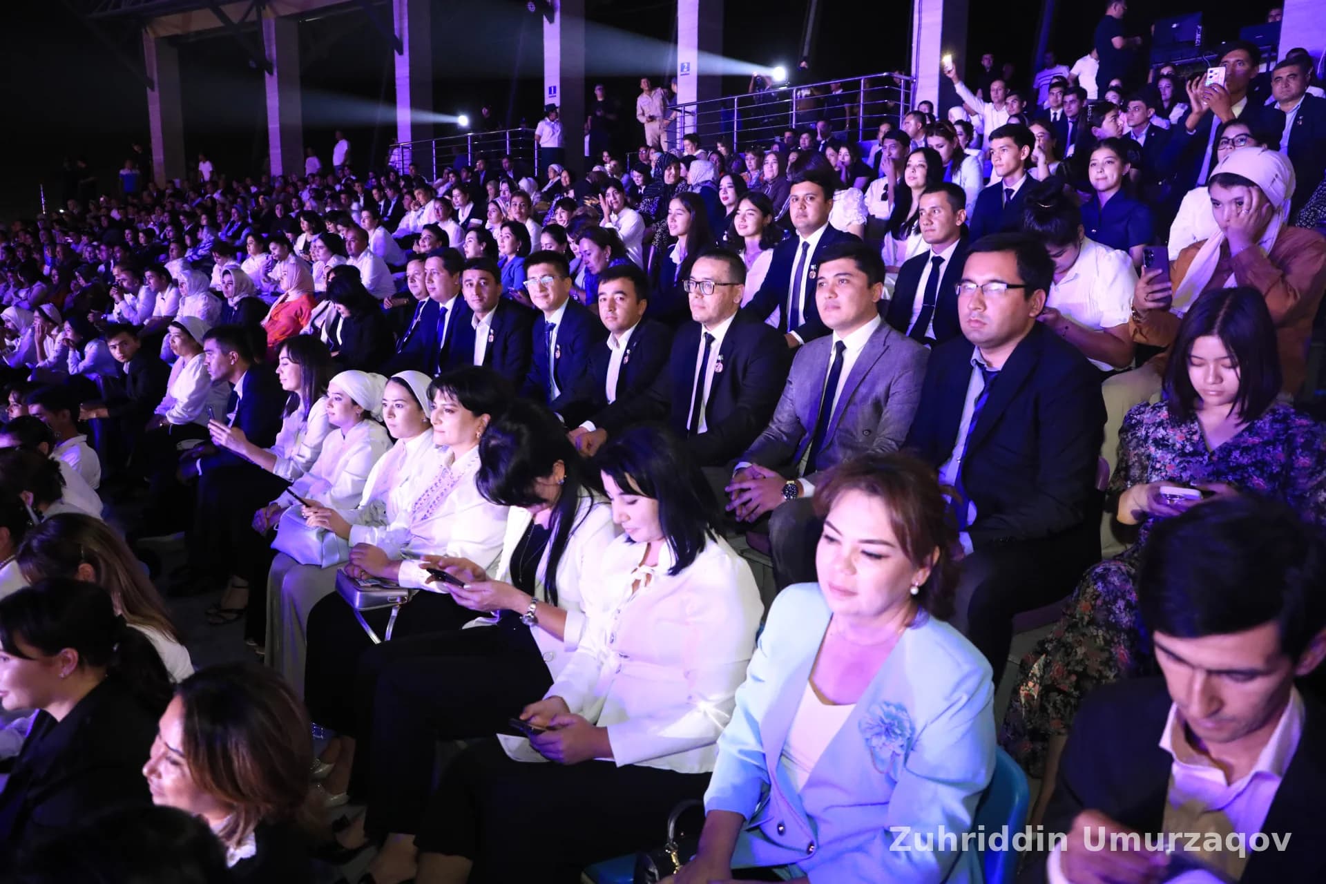 Katta auditoriyada oʻtirgan odamlar toʻdasi
