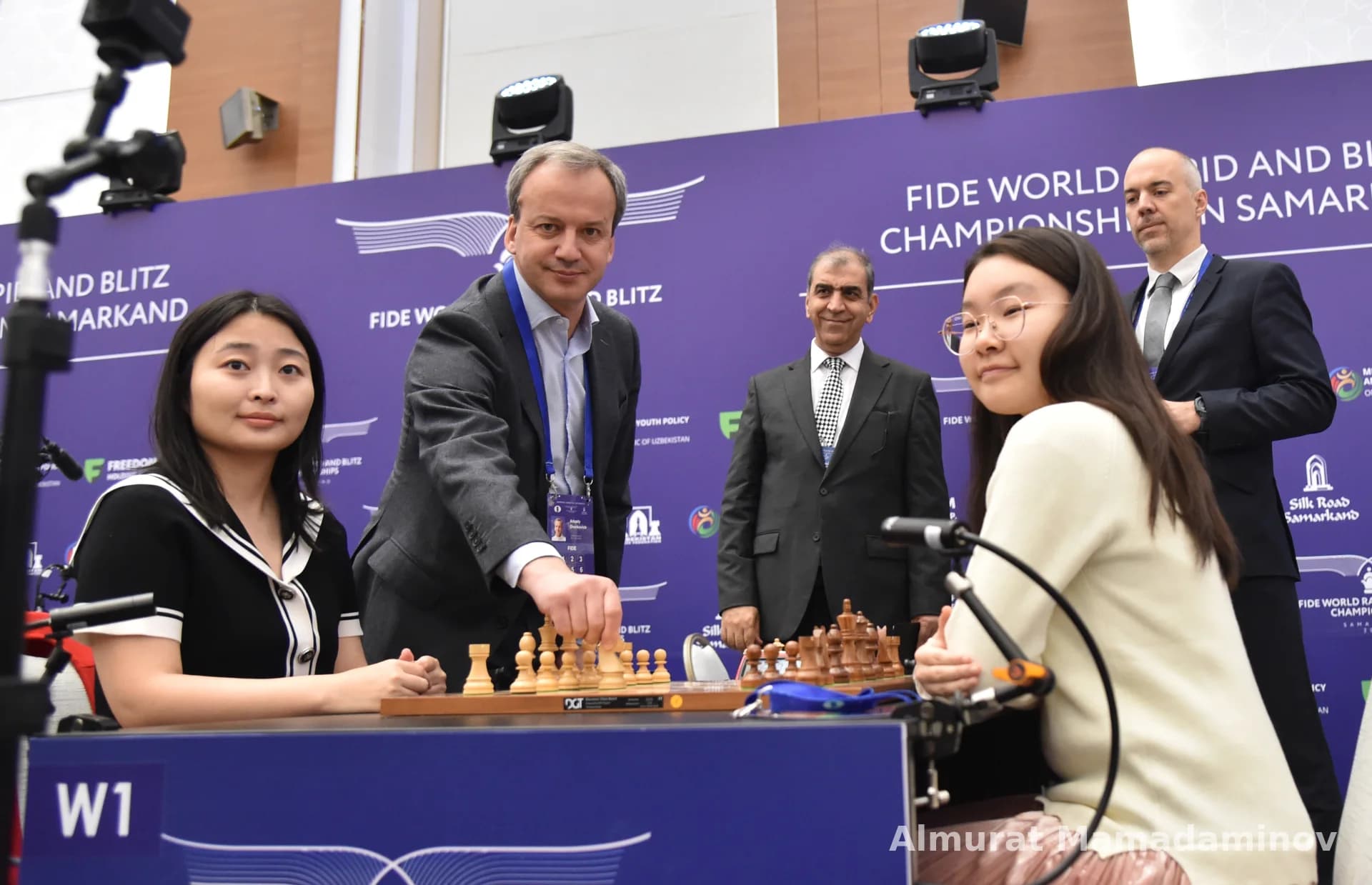 People gathered around a chess board during an indoor competition