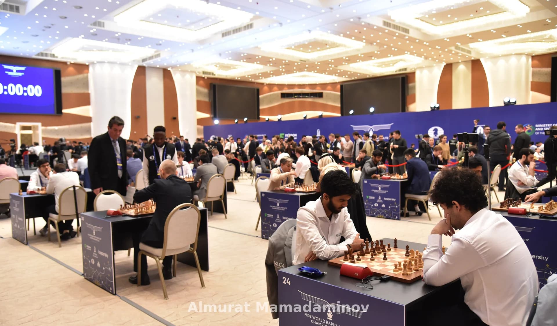 Players competing in a large chess tournament inside a hall