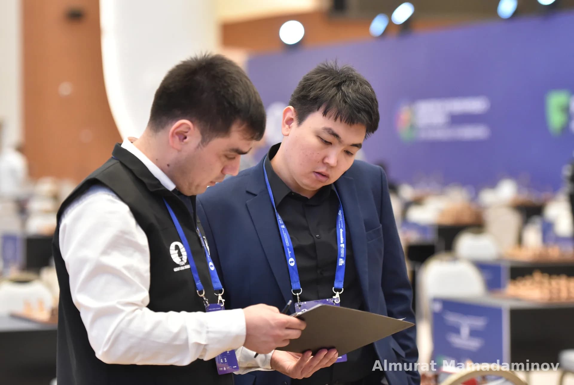 Two men reviewing documents together at an indoor venue
