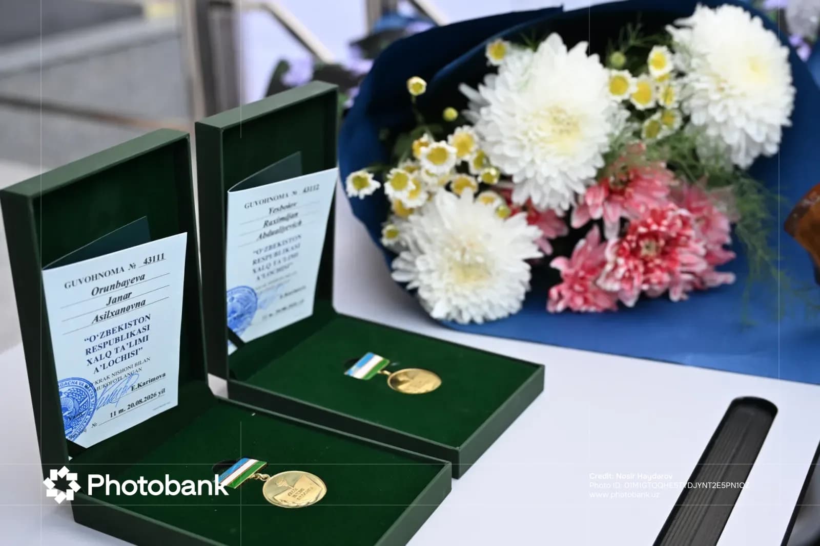 State awards and certificates in open boxes beside a bouquet of flowers