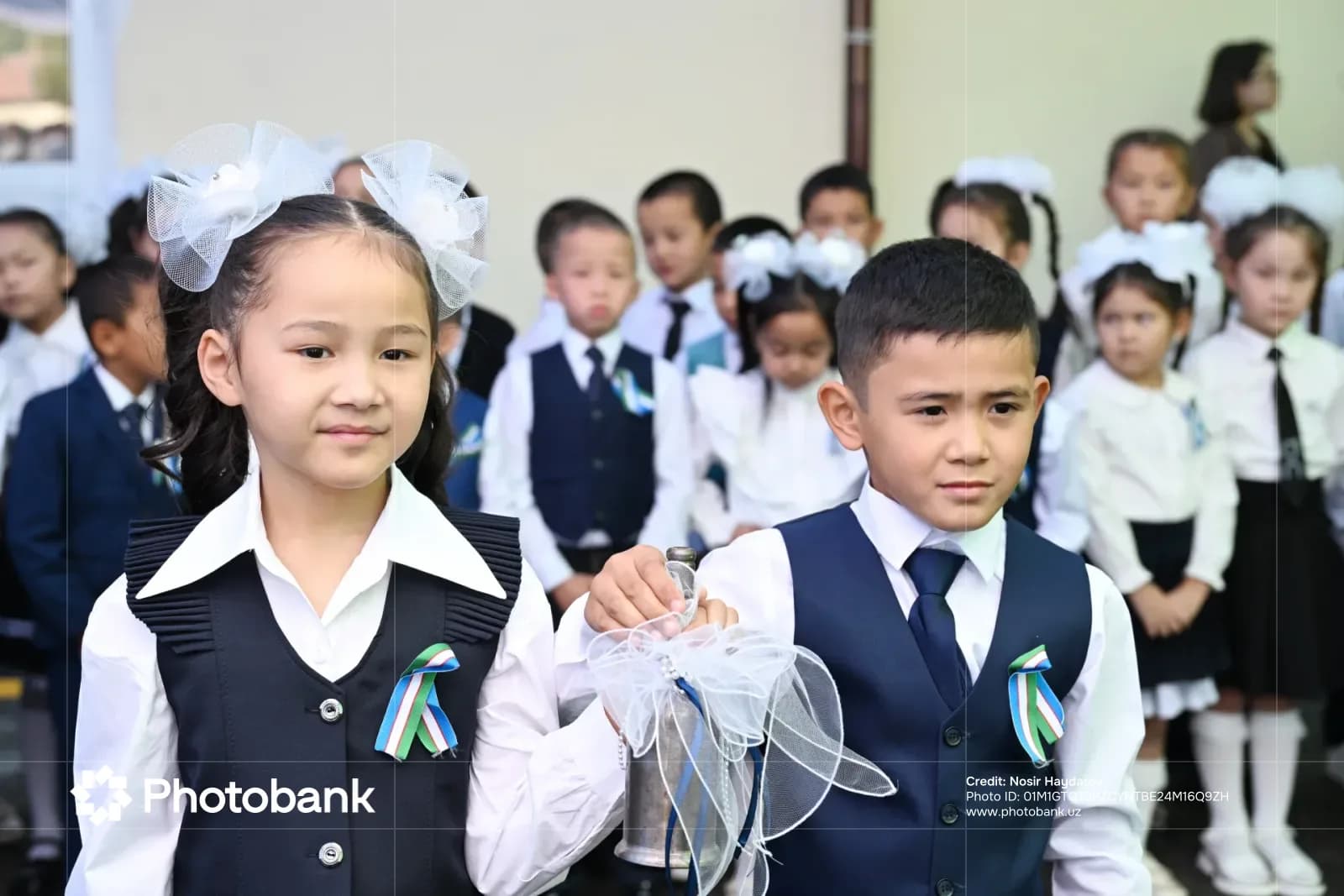 Children holding a decorative school bell in a group