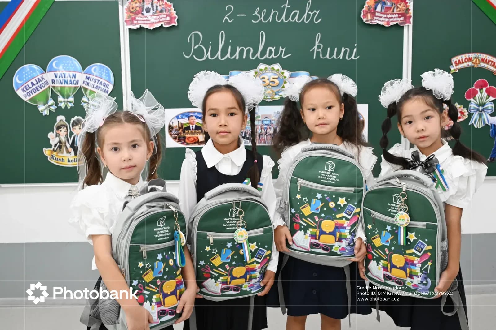 Young girls posing with school backpacks in a classroom