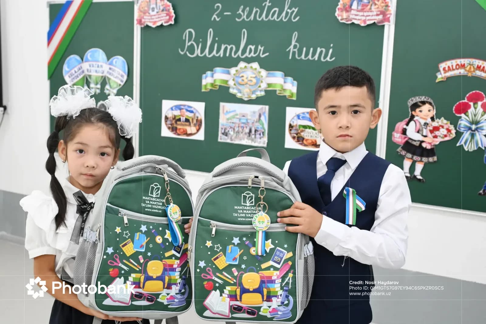 Children holding school backpacks in a classroom
