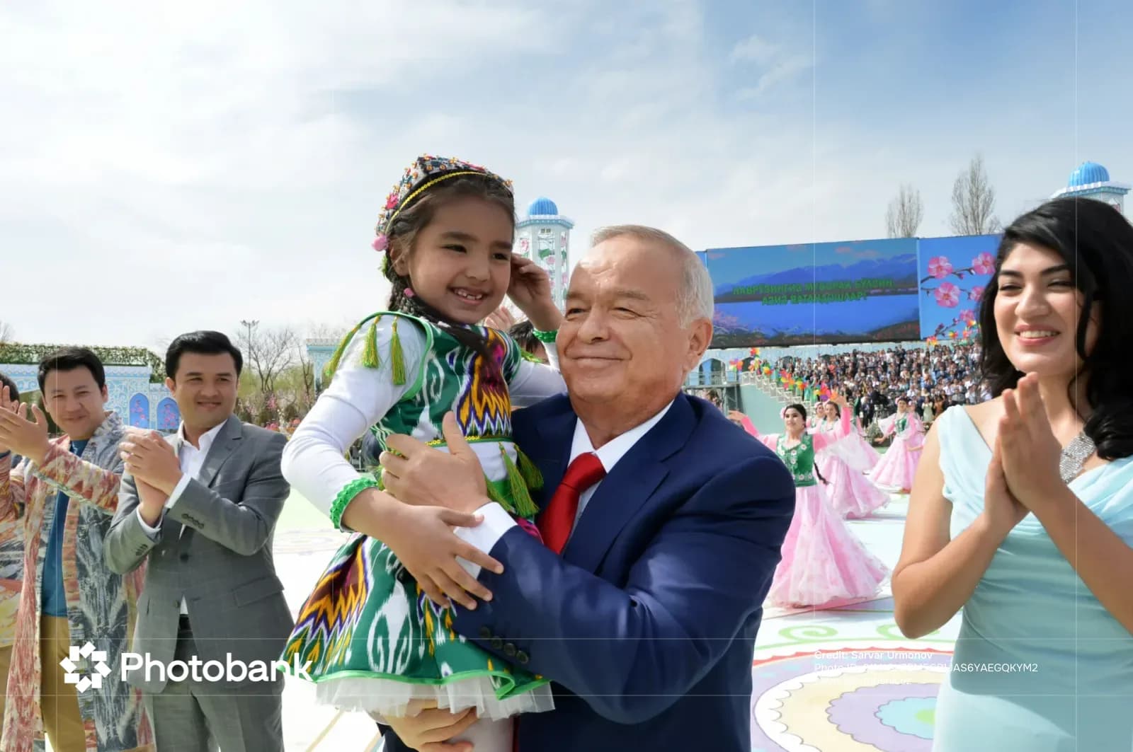 An adult holding a child in traditional clothing outdoors