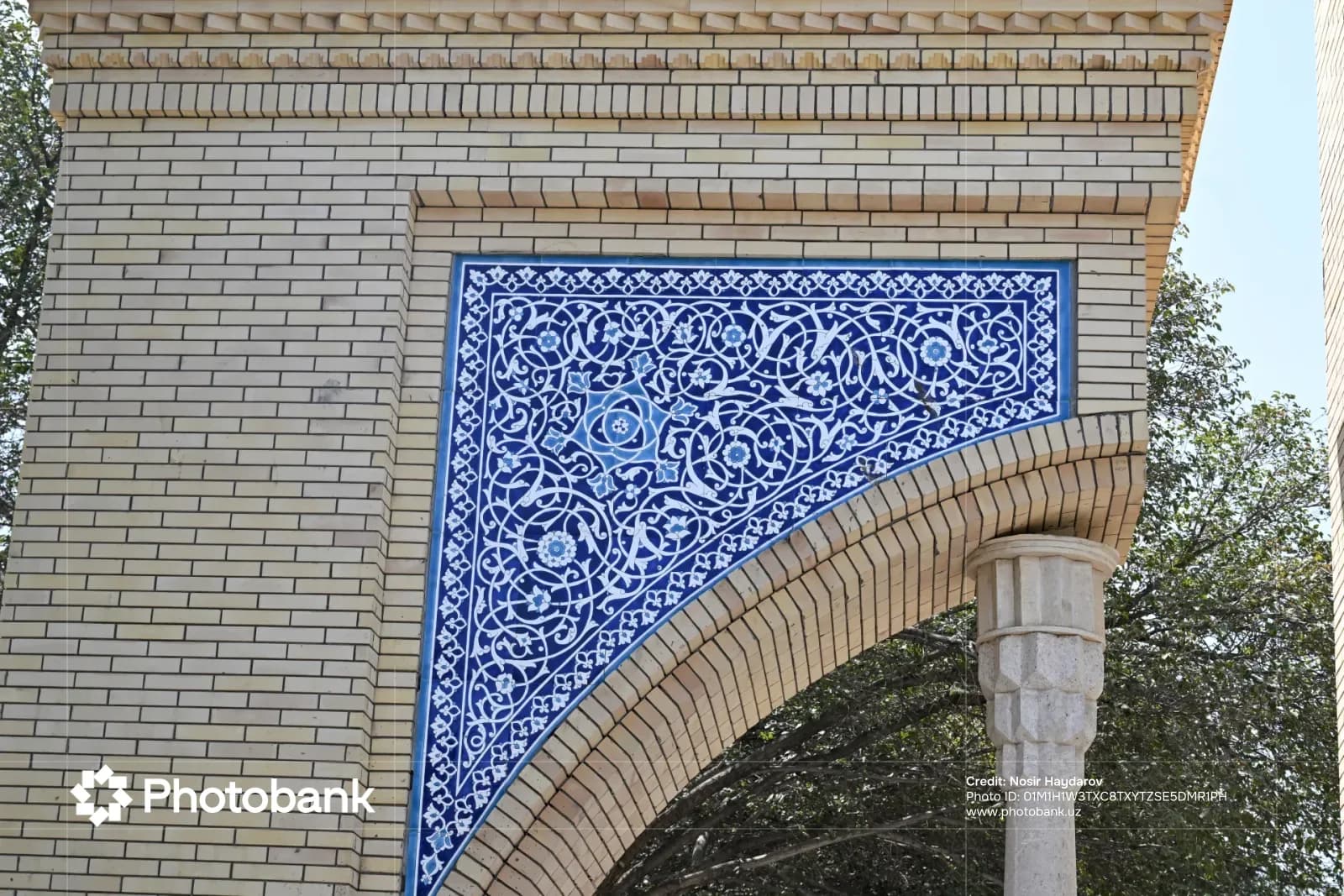 Сложная работа с синими керамическими плитками, украшающая внешнюю кирпичную арку