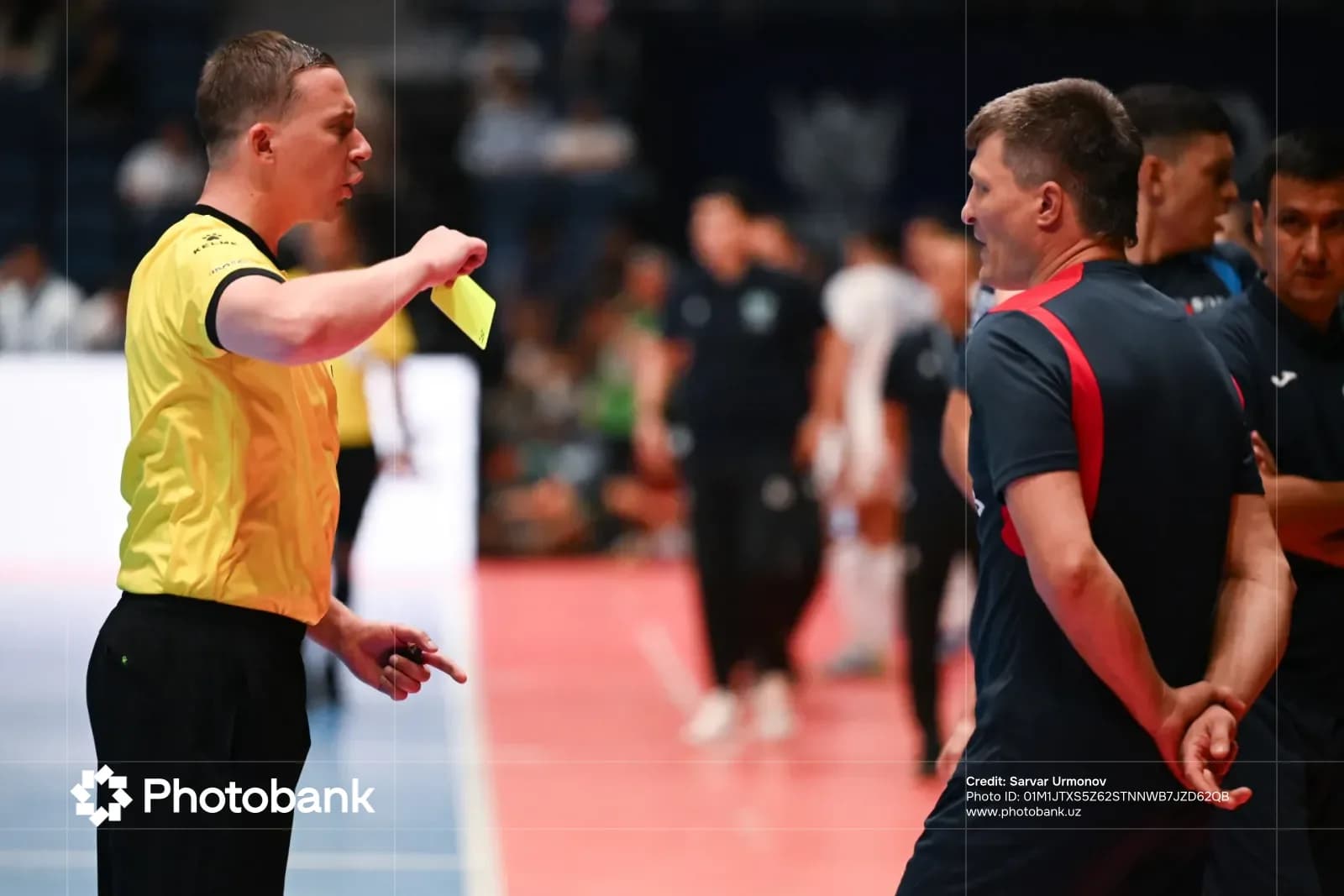 Referee holding a yellow card during an indoor sports competition