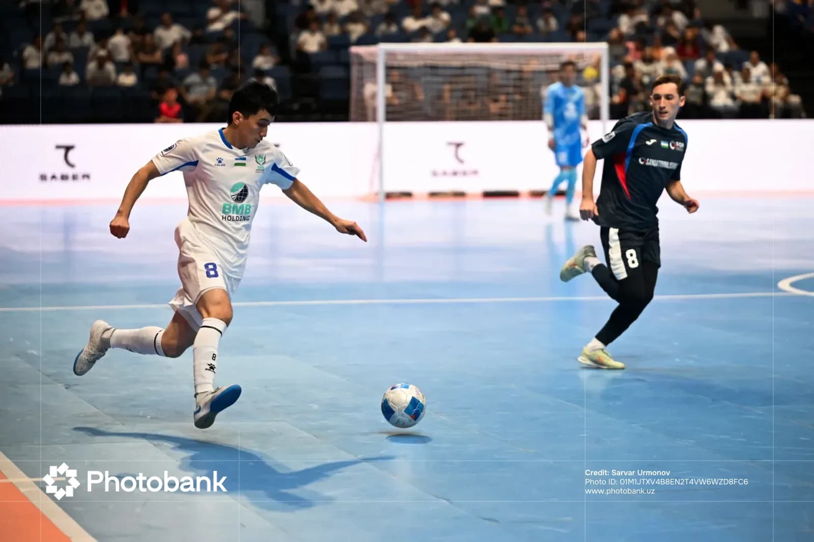 Indoor soccer player dribbling the ball on a court during a match