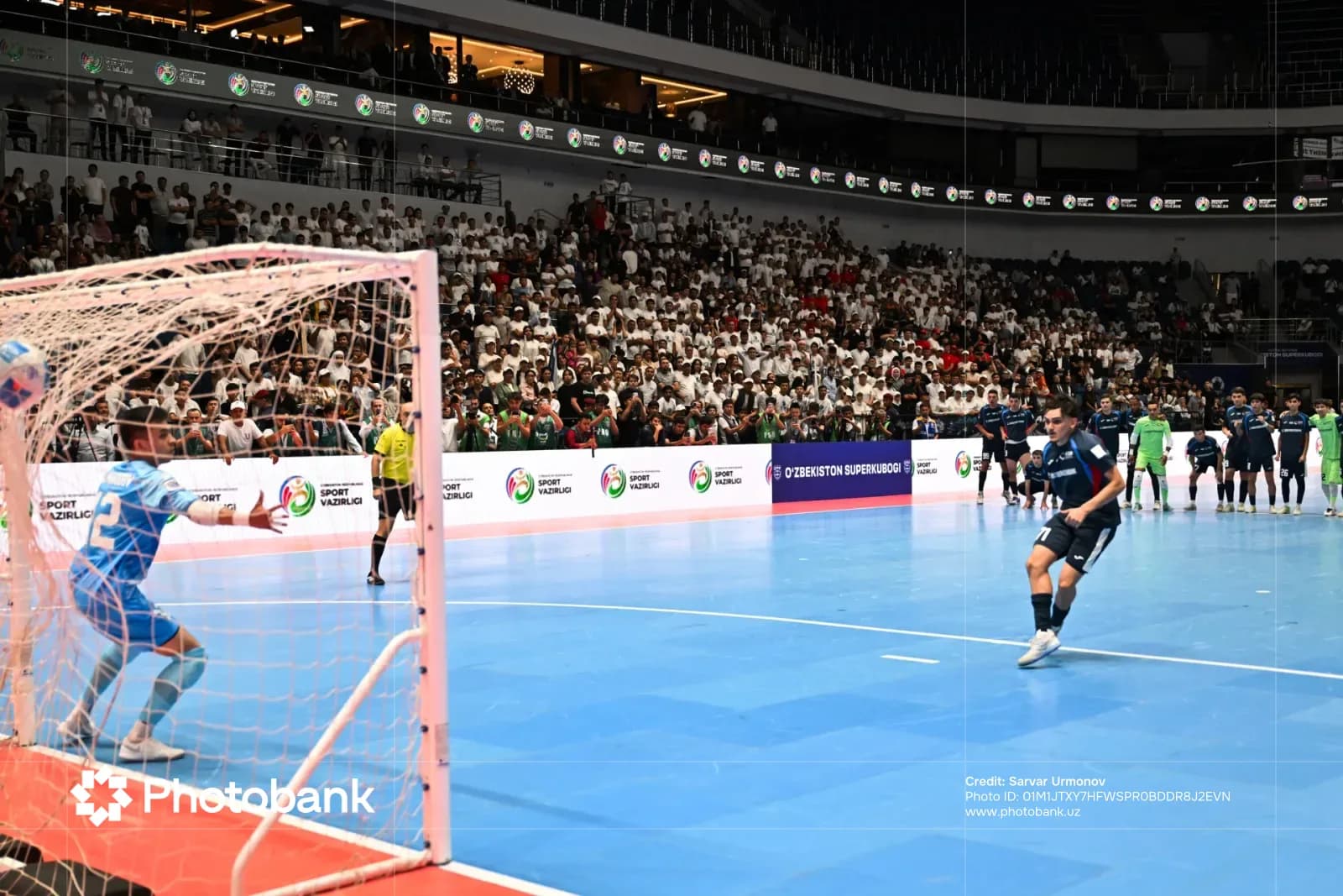 Futsal penalty kick in indoor arena with spectators