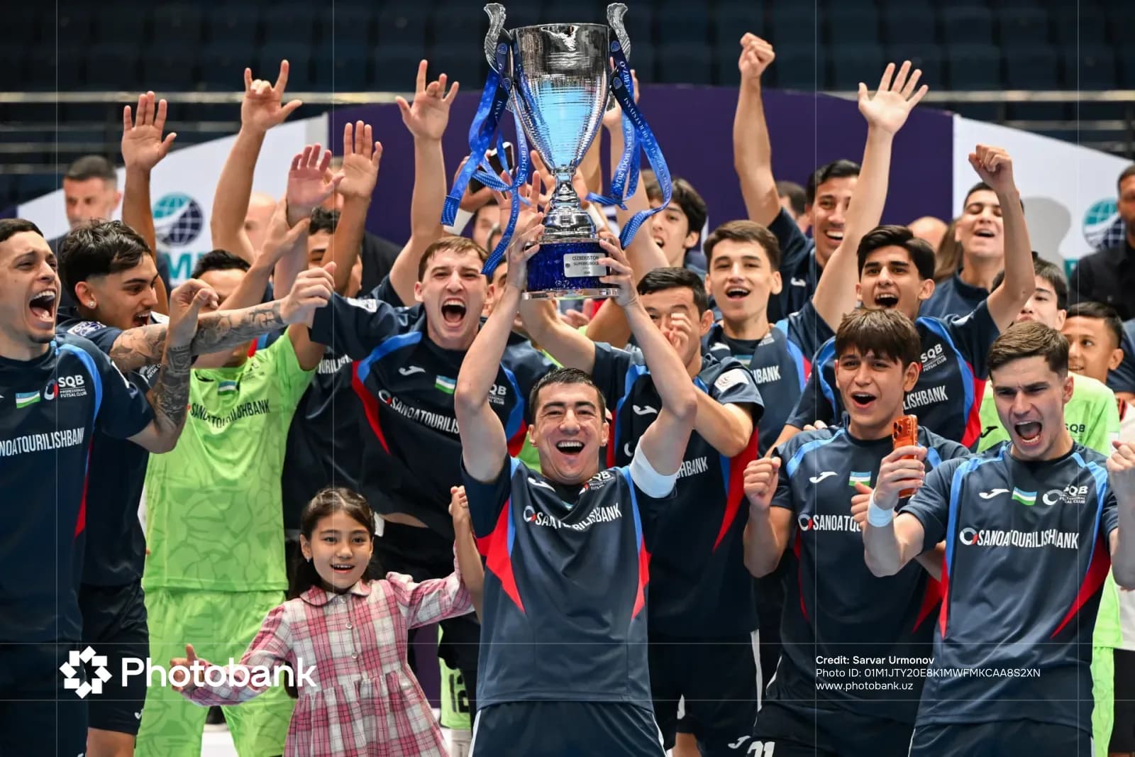 Athletes celebrating with a large trophy after a sports victory
