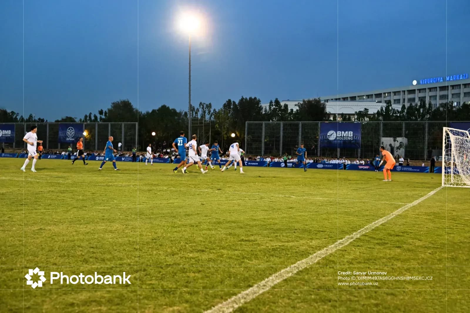 Football match played on an outdoor grass field under stadium lights