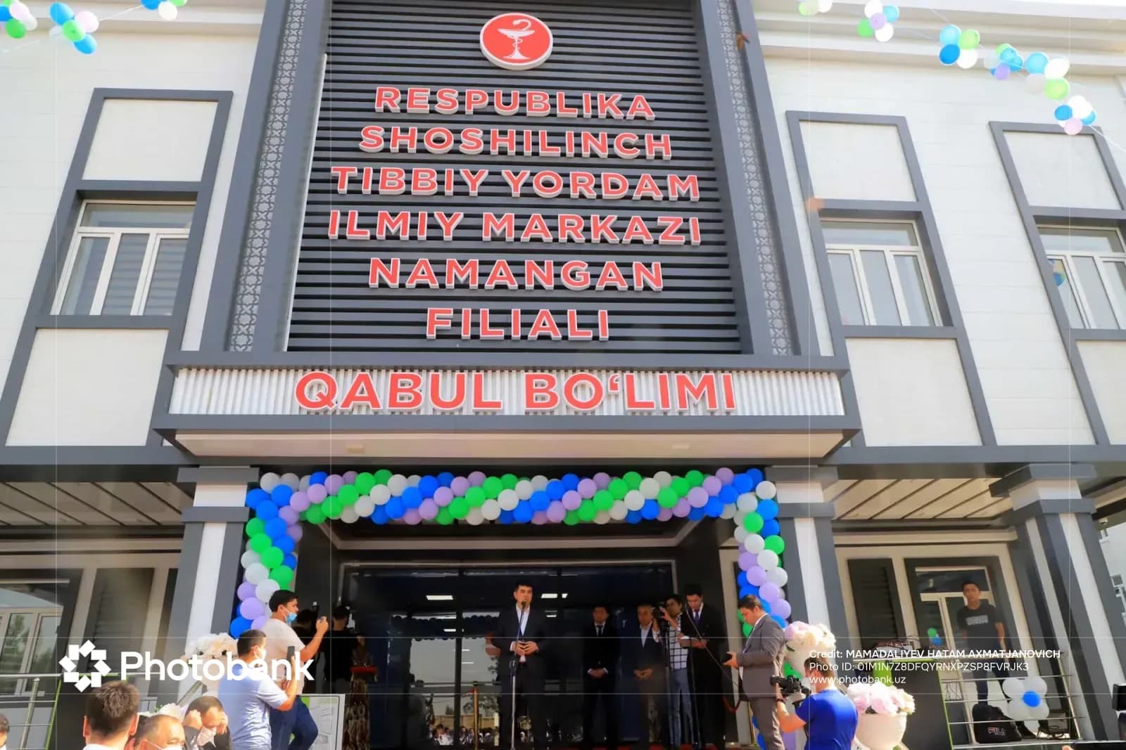 Building facade with red lettering and people gathered at the entrance