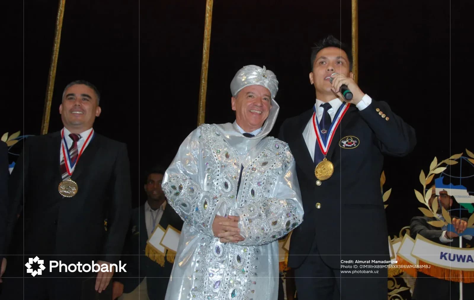 People posing with medals and traditional attire on stage