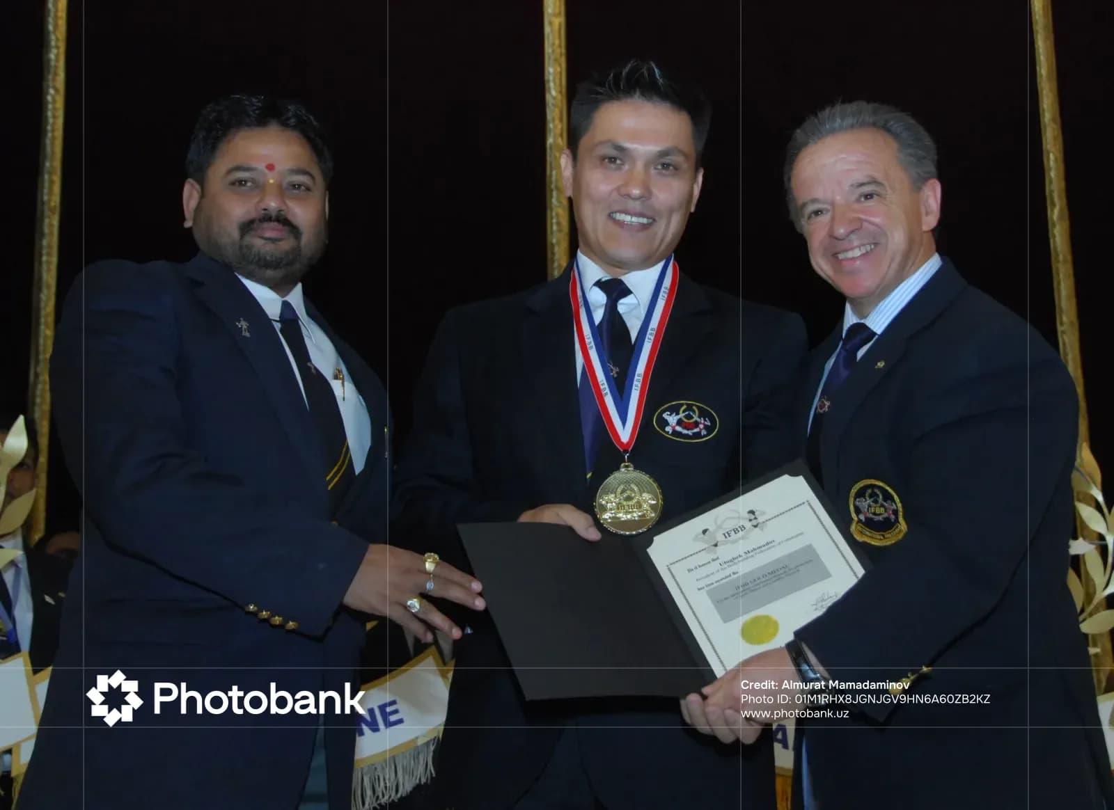Three men posing with a medal and a certificate