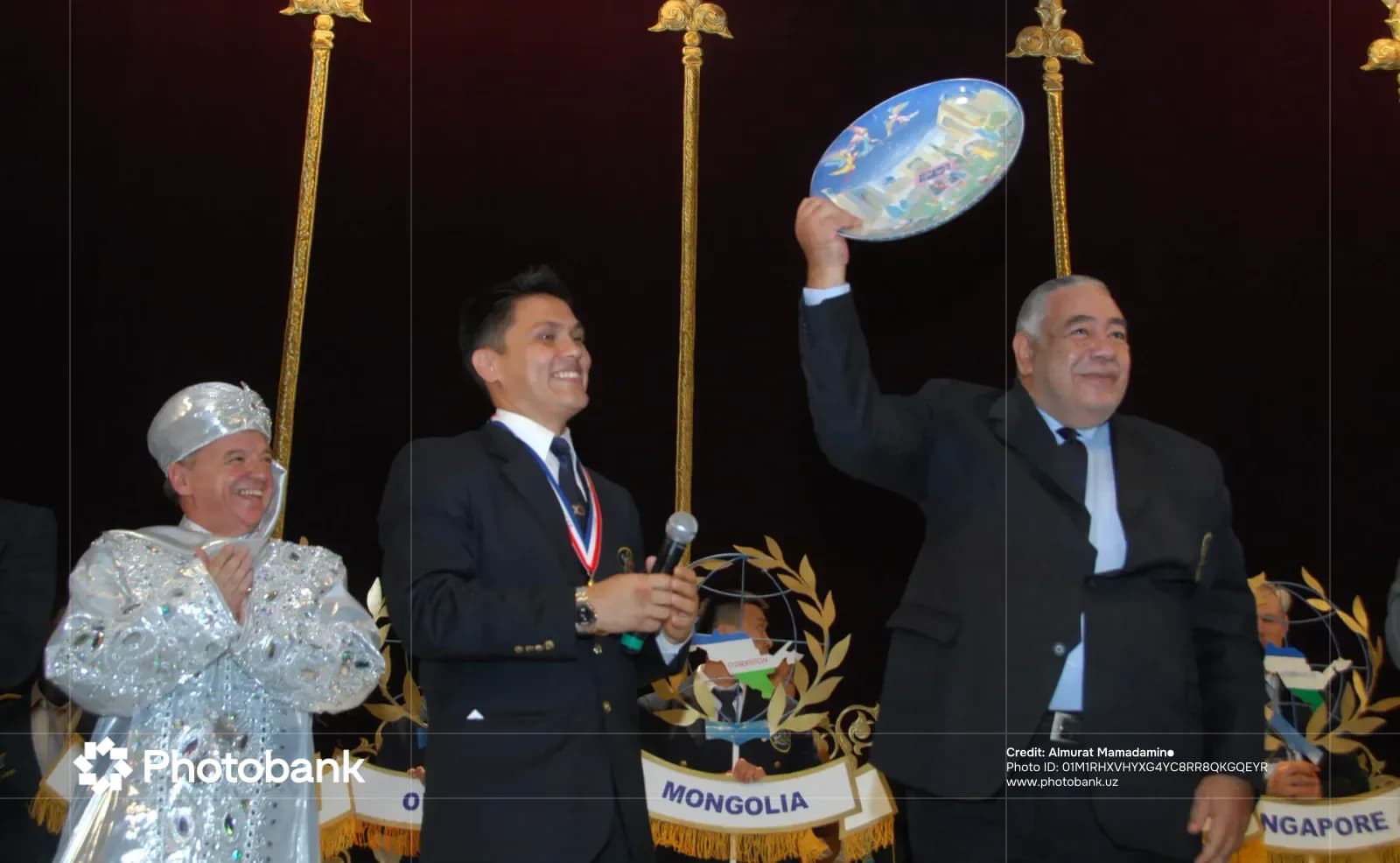 People holding a decorative plate on stage