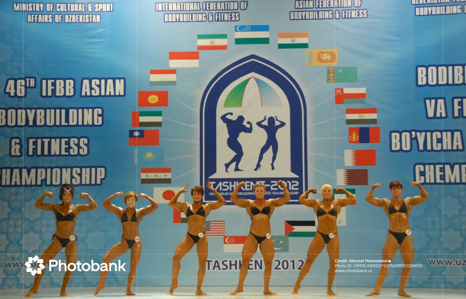Female athletes pose on stage during bodybuilding competition