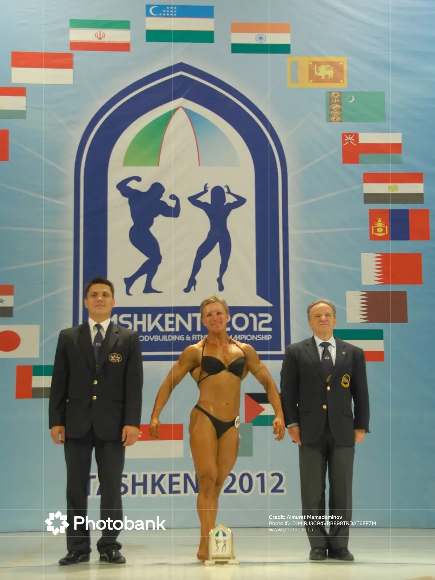 Athletes and officials stand on stage at a bodybuilding competition