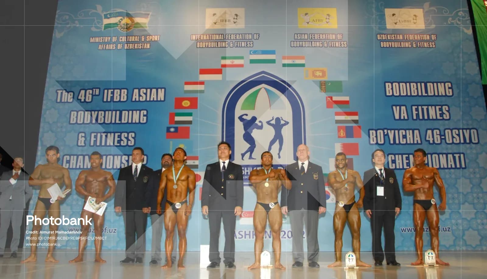 Bodybuilders and officials posing on stage at a championship event